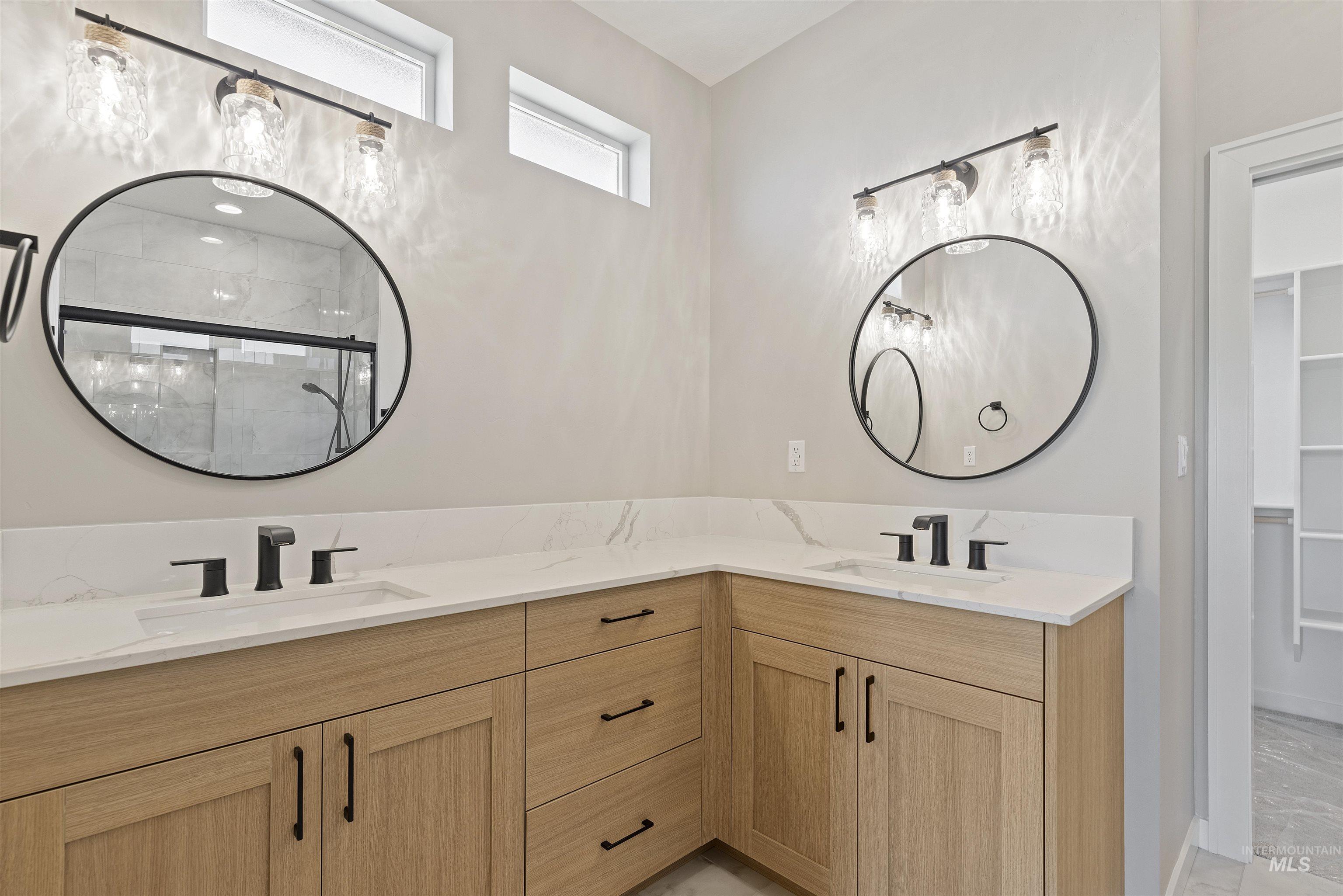 Full bath with double vanity, tiled shower, a spacious closet, and marble finish floors