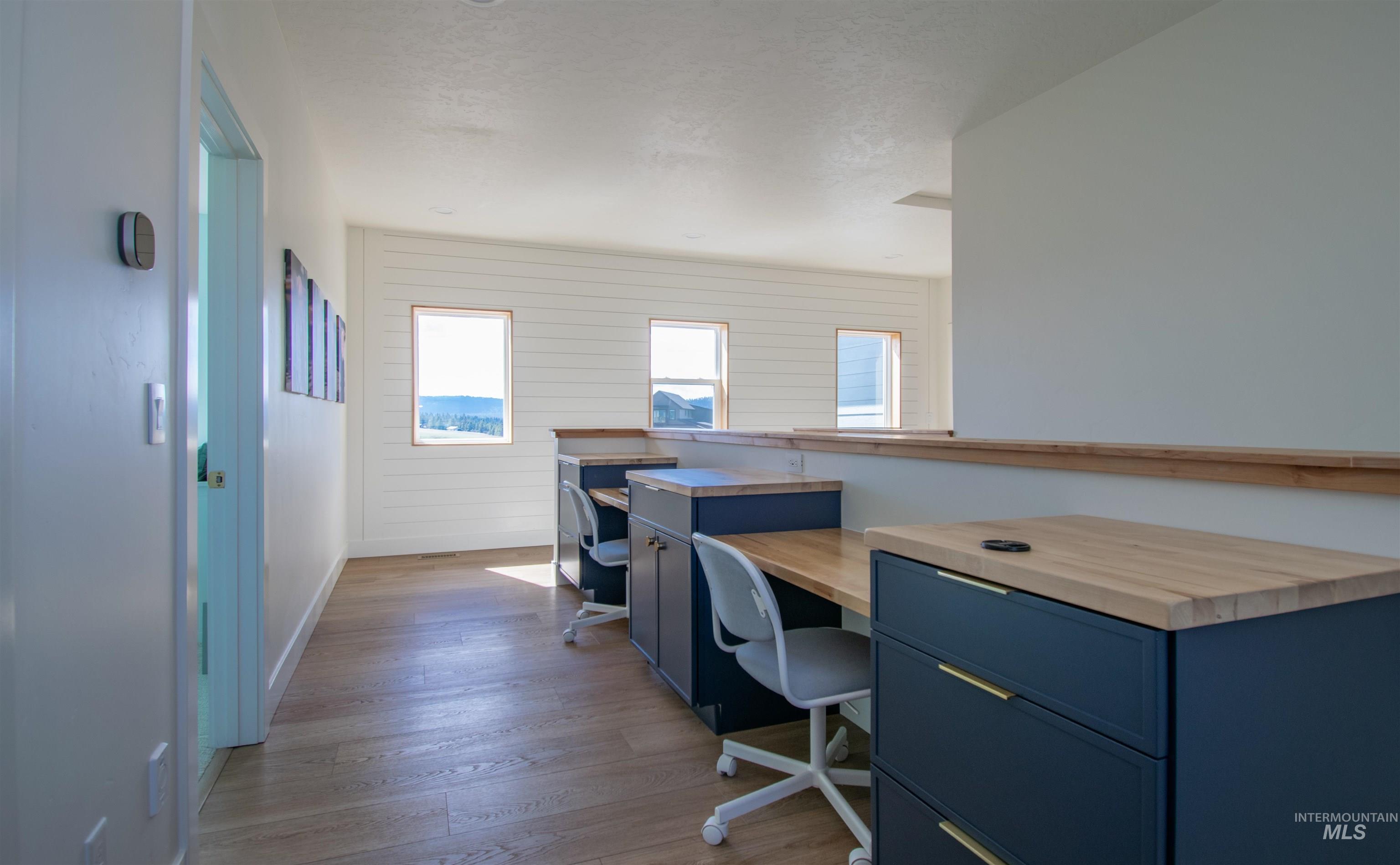 Dedicated workstation area featuring wood-finish flooring and integrated desk cabinetry with wood countertops