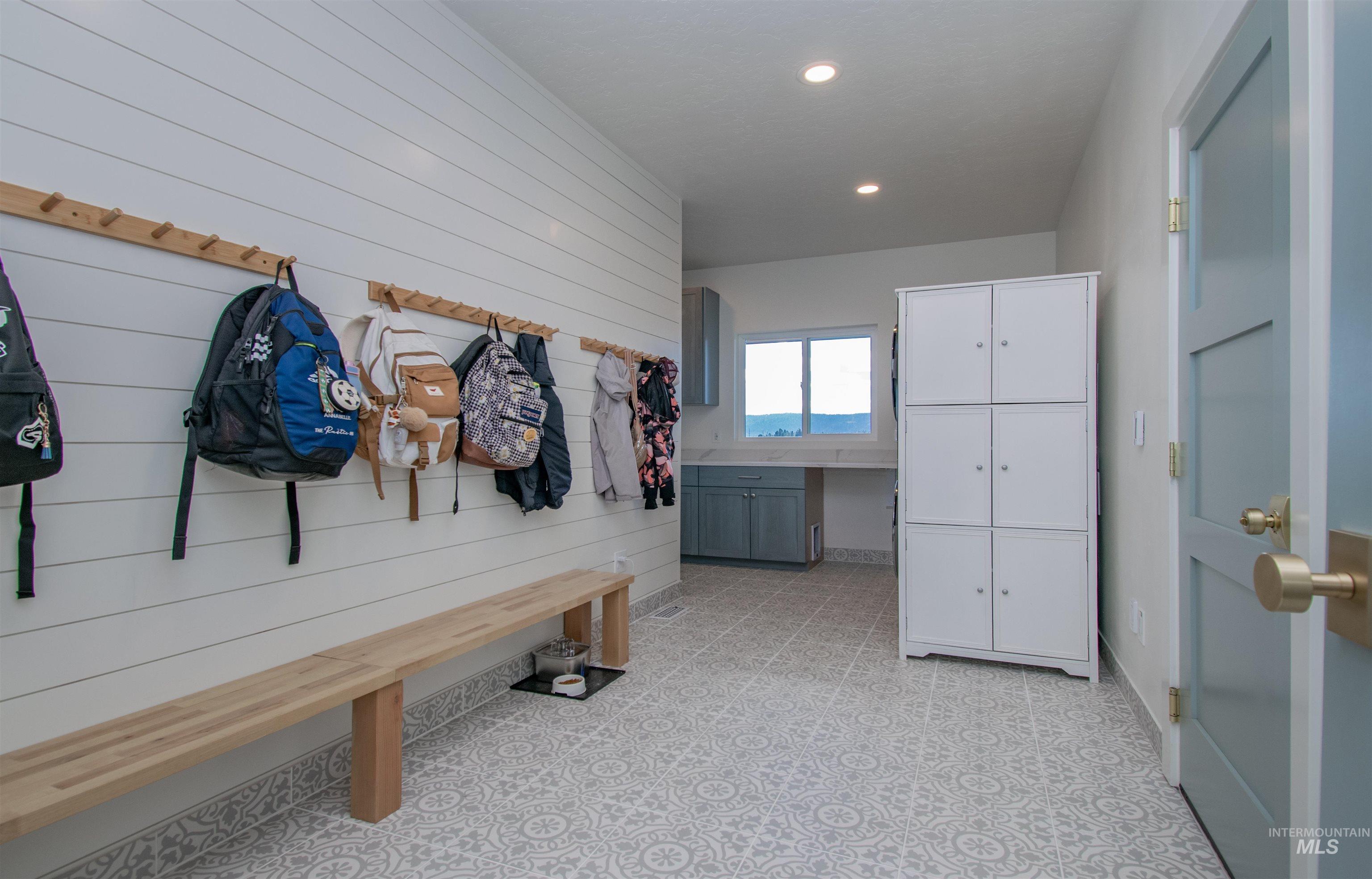 Entryway featuring shiplap wall paneling, a built-in wooden bench, and a peg rail system