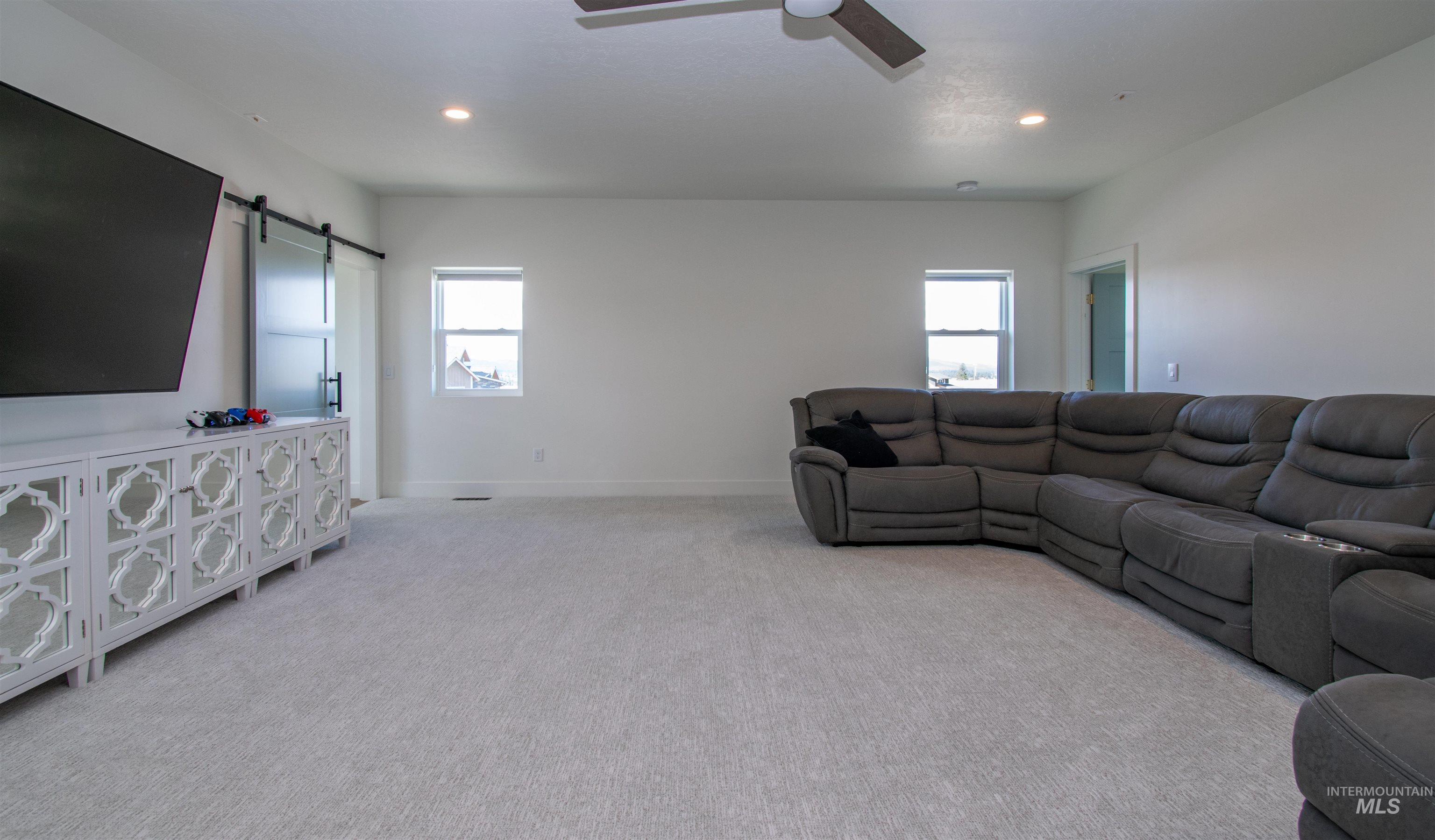 Spacious carpeted room featuring recessed lighting, a ceiling fan, and two windows providing natural illumination