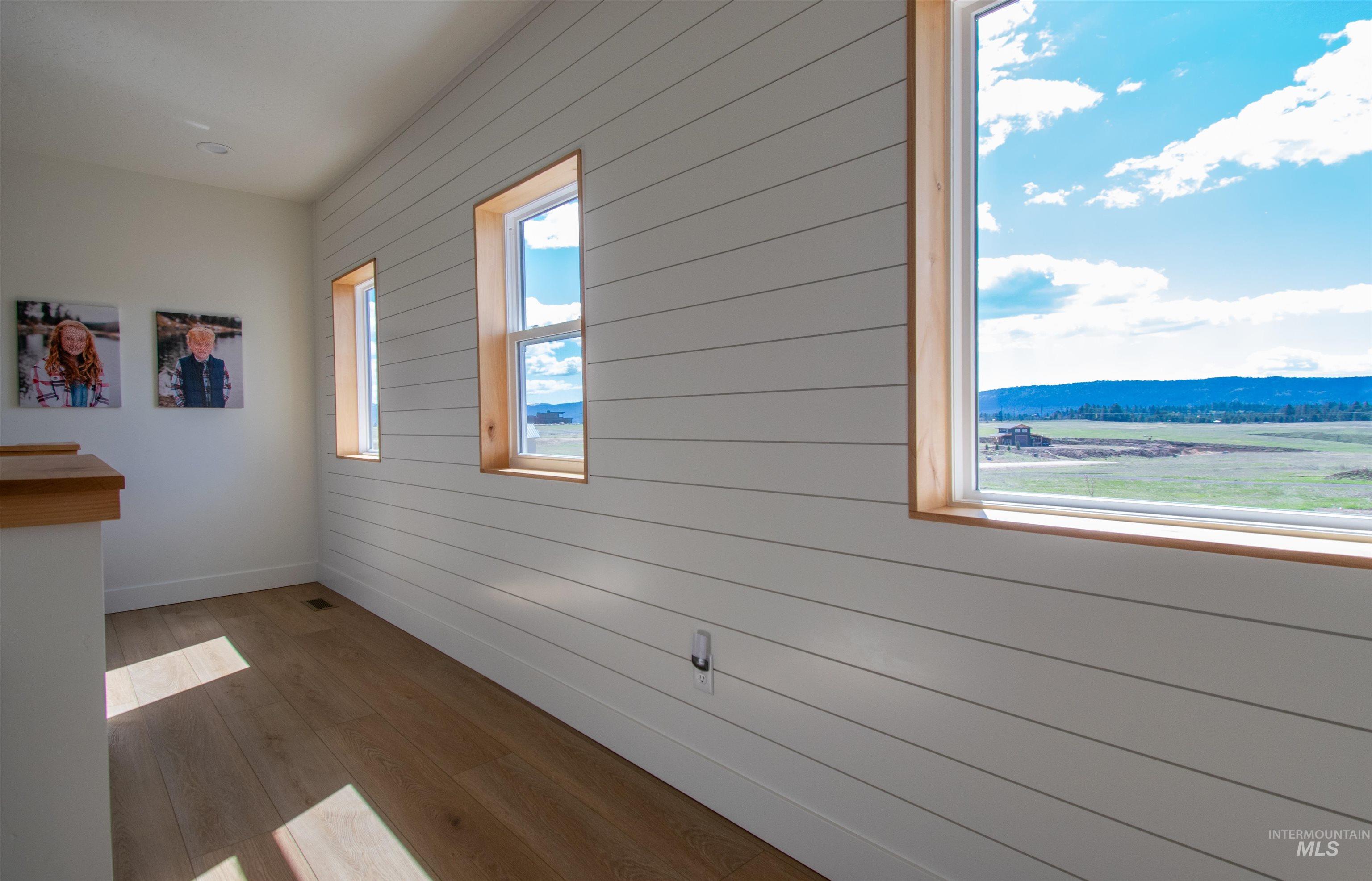 Interior space featuring white shiplap wall paneling and warm wood-finish flooring