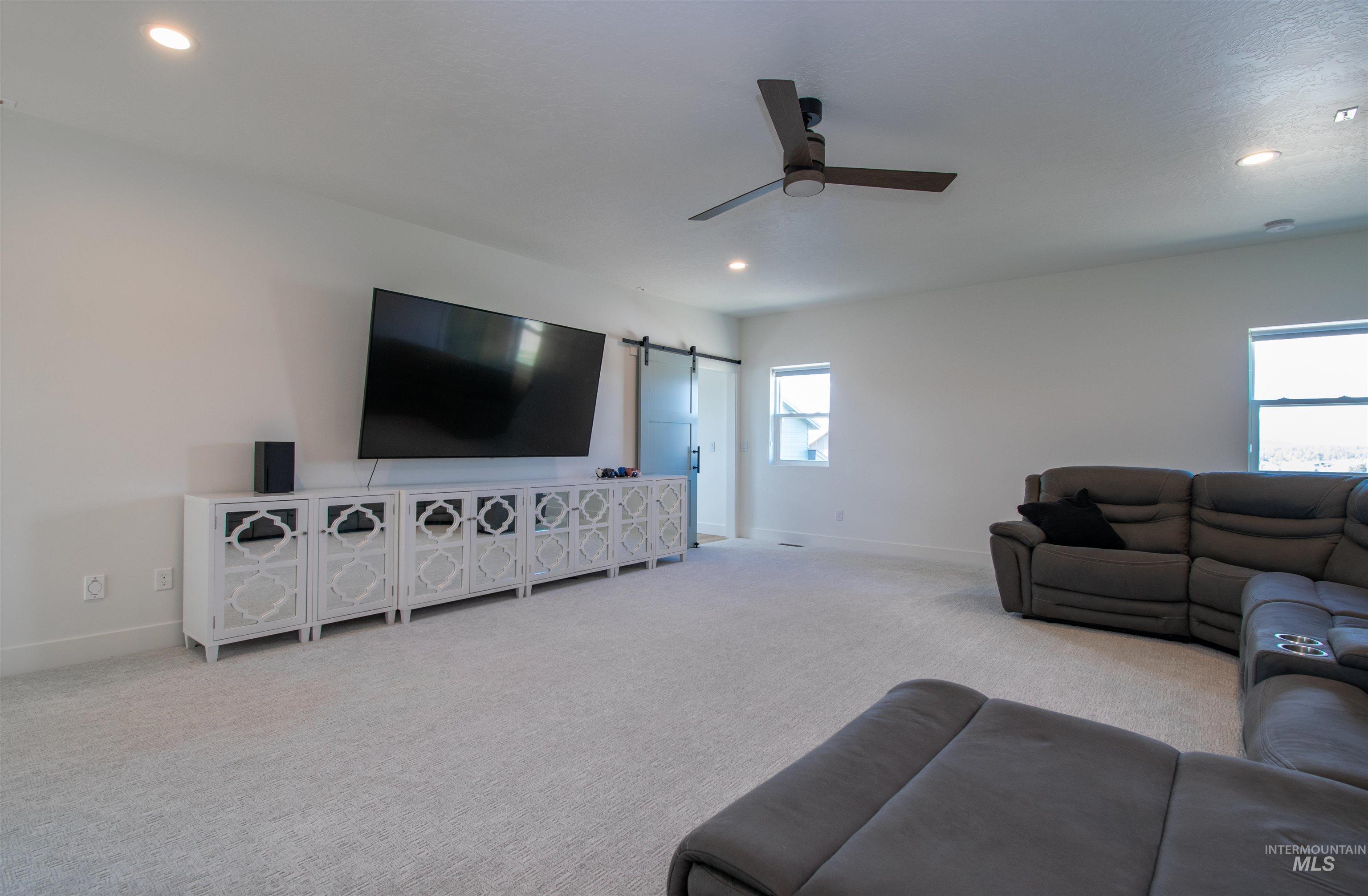 Spacious room featuring light-colored carpeting, multiple recessed lighting fixtures, and a ceiling fan