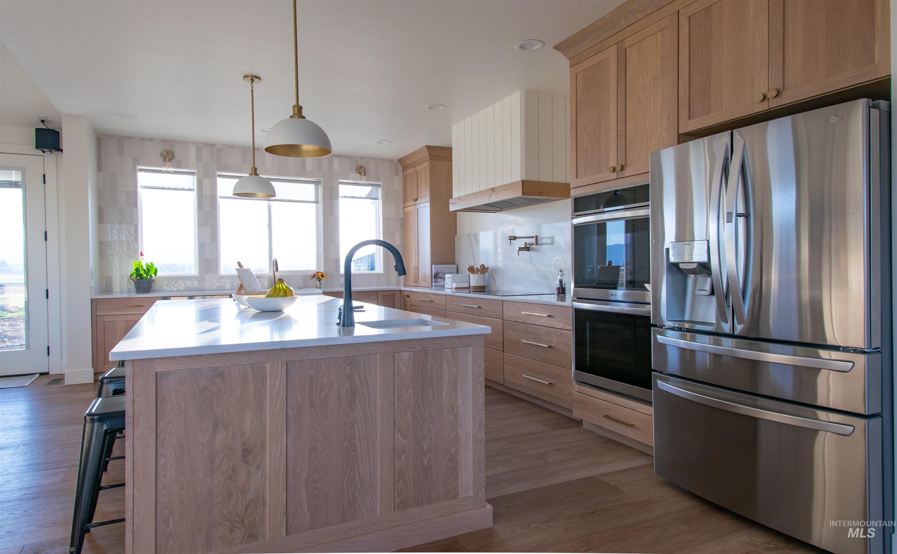 Bright kitchen featuring light wood-finish cabinetry and a large center island with a white countertop