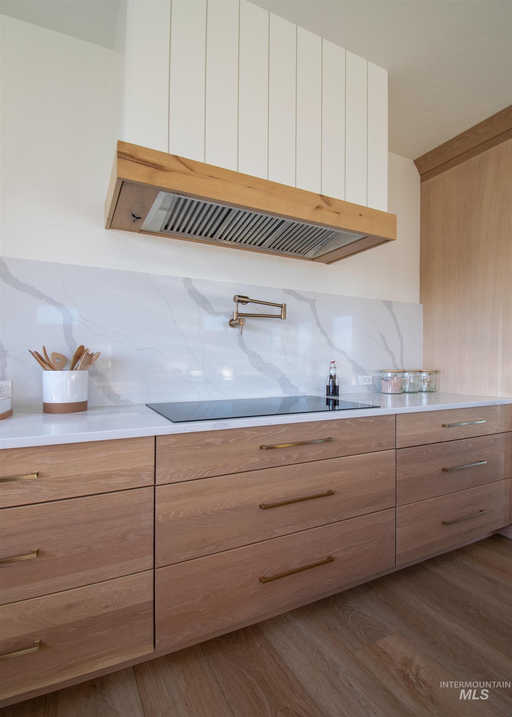 Modern kitchen featuring light wood-finish cabinetry with brass hardware