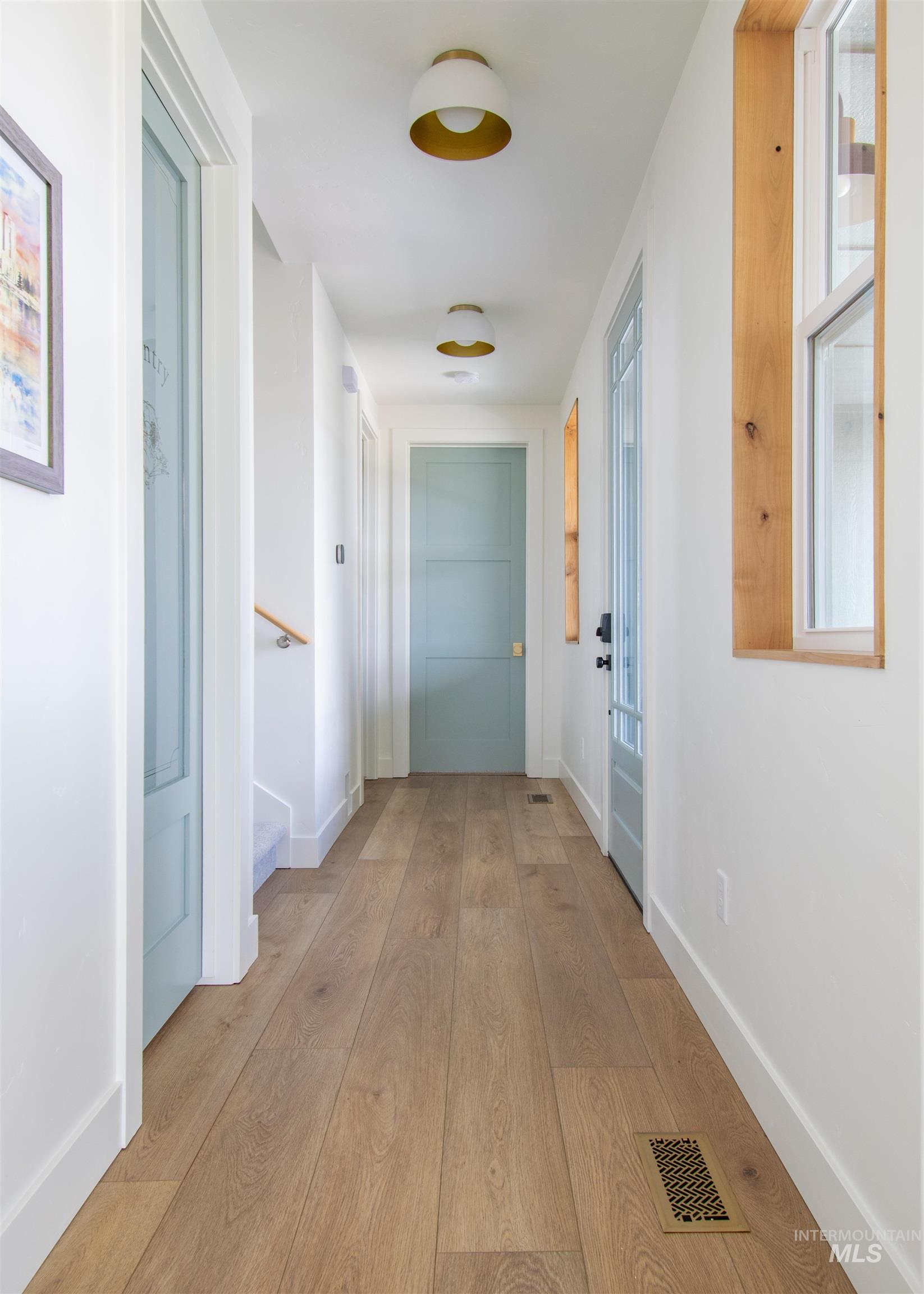 Hallway featuring wood-finish flooring, white walls, and light blue doors