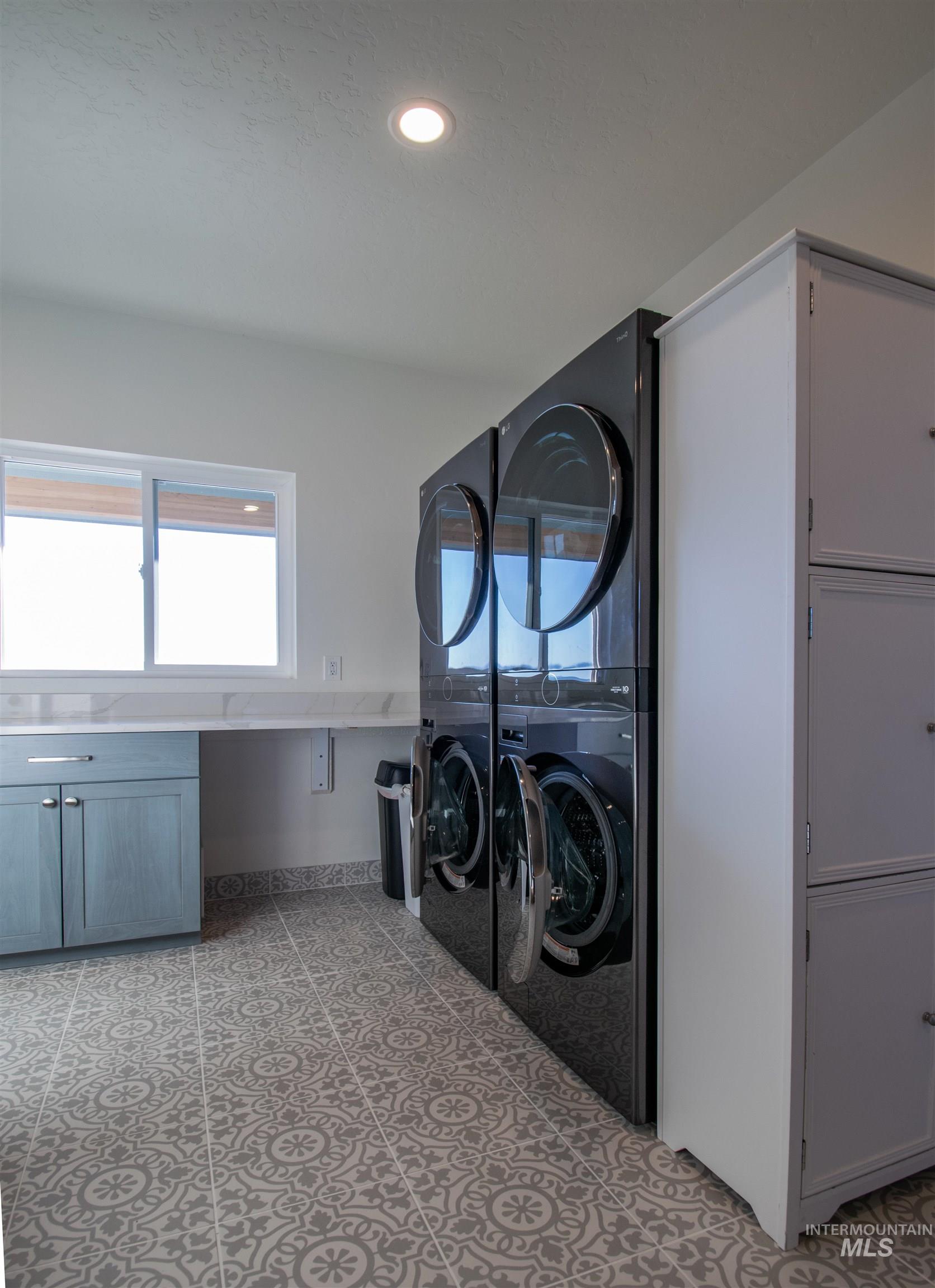 Laundry room featuring patterned floor tiles, recessed lighting, a built-in countertop with an undermount sink, and light blue cabinetry with brushed nickel hardware