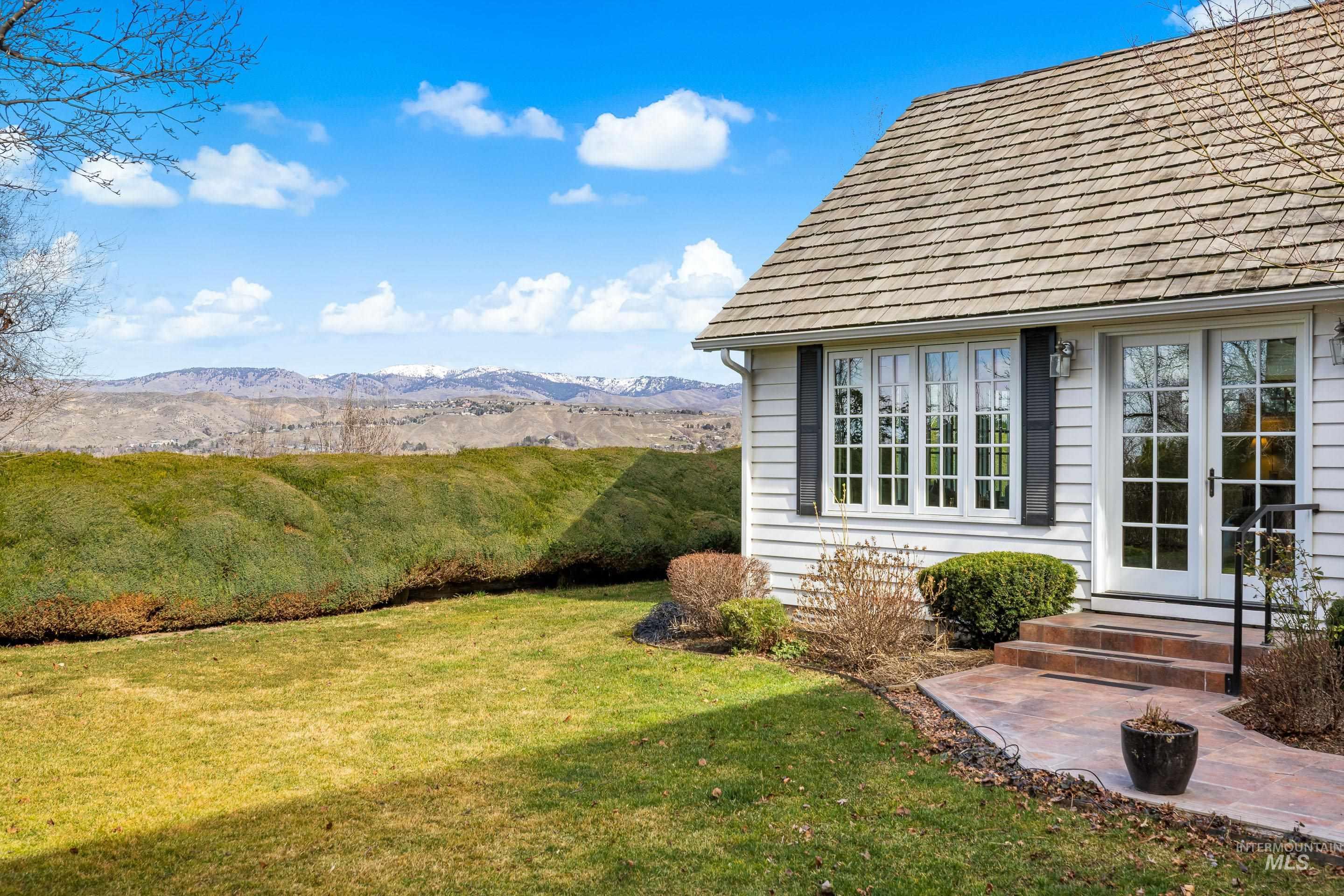 View of green lawn featuring french doors and a mountain view