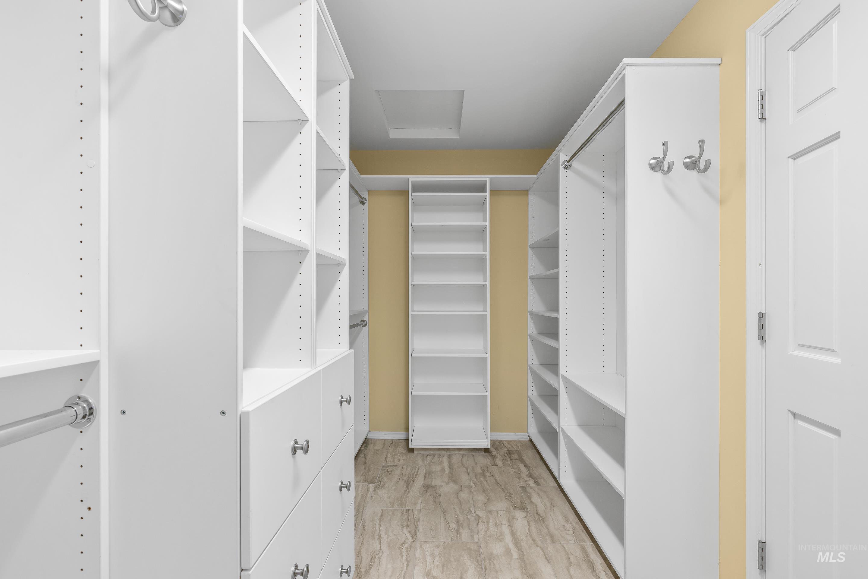 Walk in closet featuring attic access and light wood finished floors