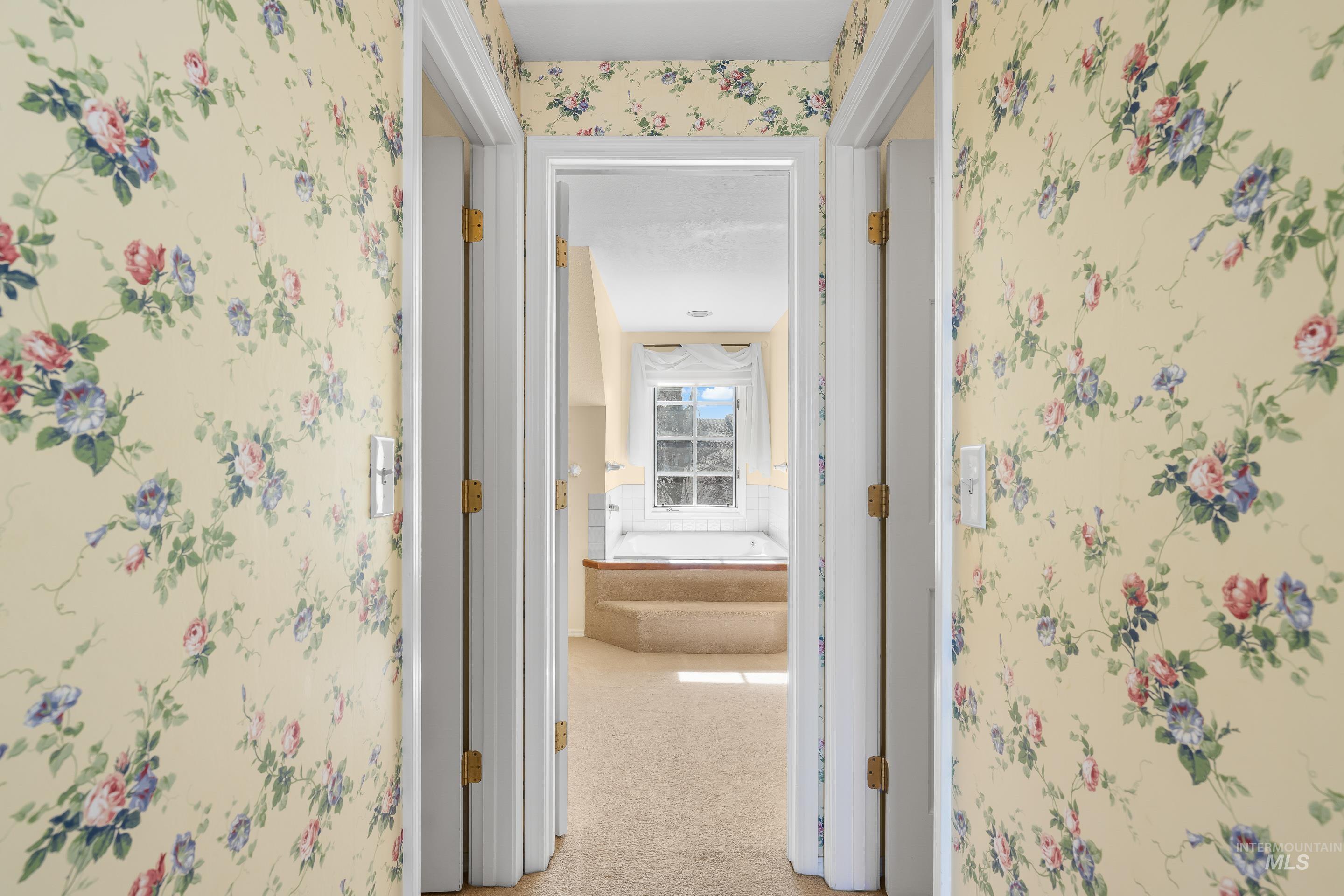 Hallway featuring wallpapered walls and light colored carpet