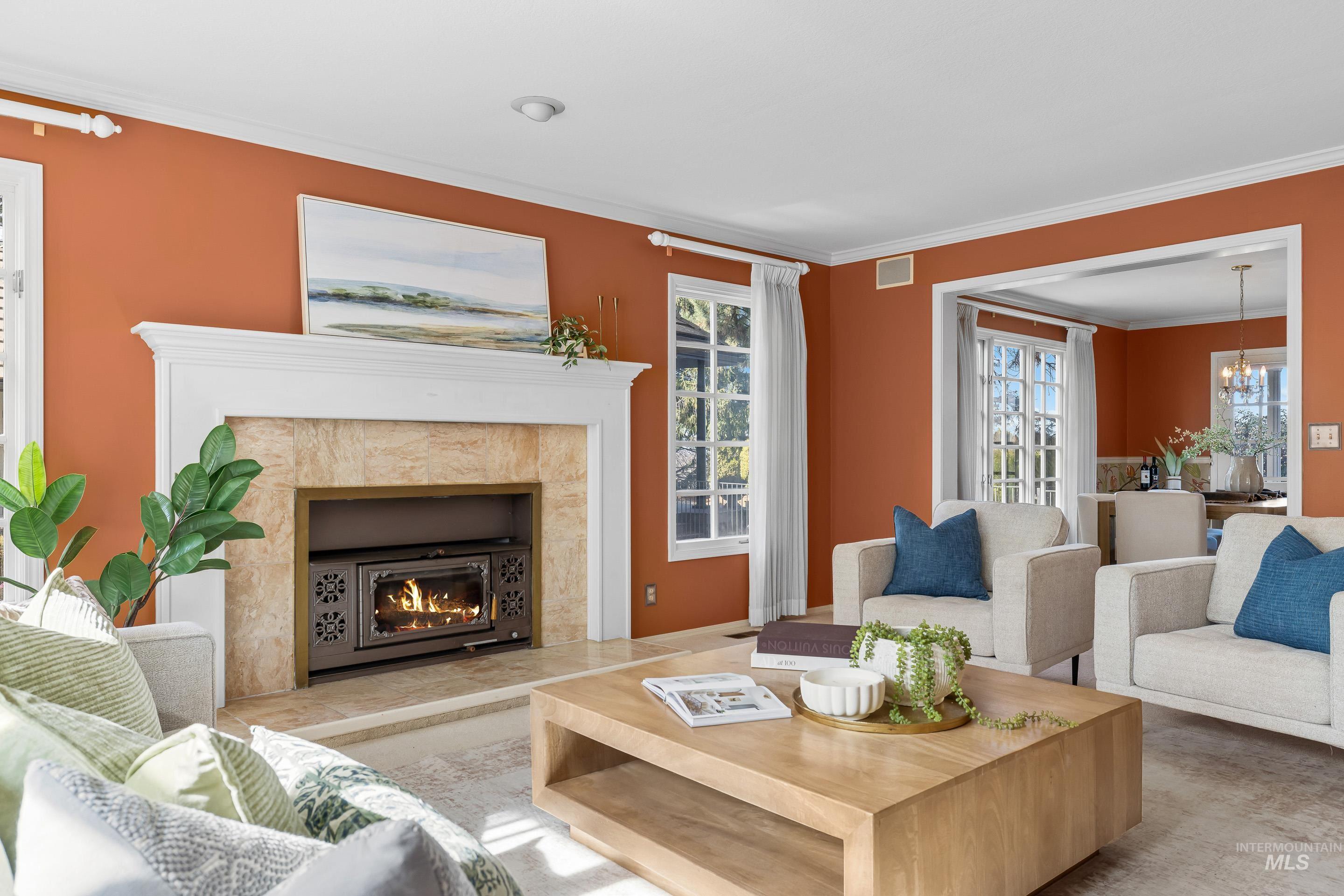 Living room with crown molding, hanging lights, and a fireplace