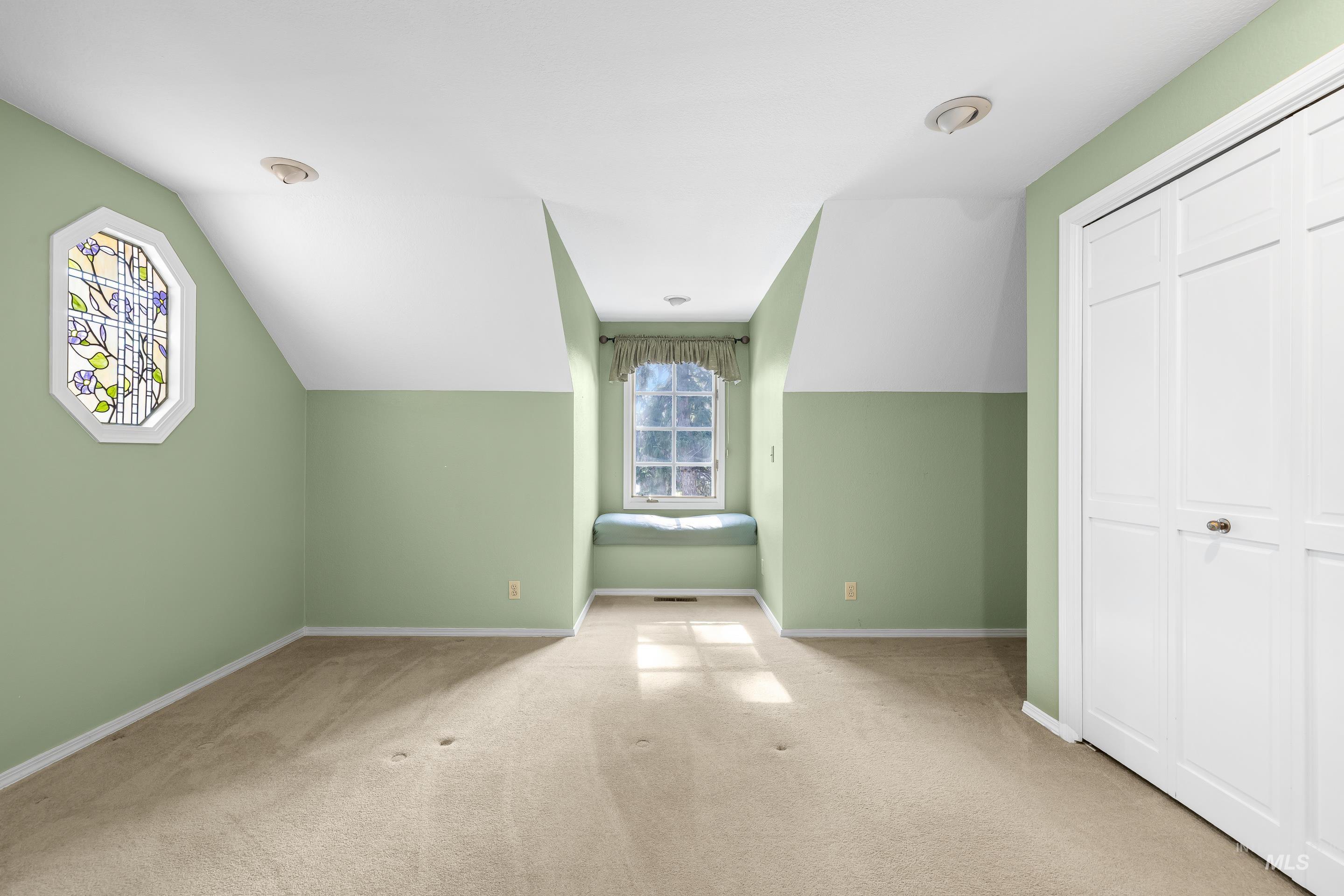 Additional living space with lofted ceiling and light carpet