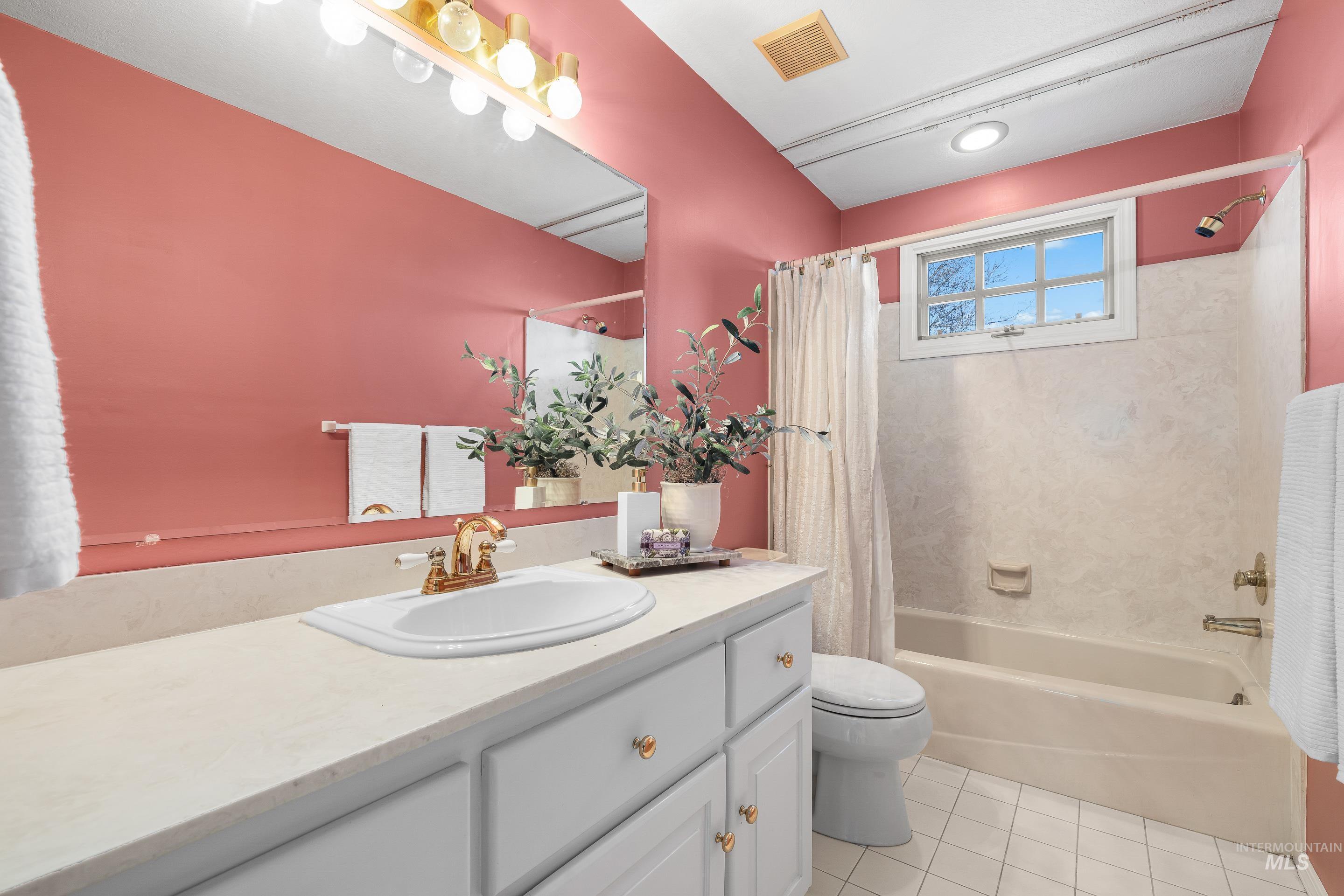 Bathroom featuring vanity, shower / bath combo, and light tile patterned flooring
