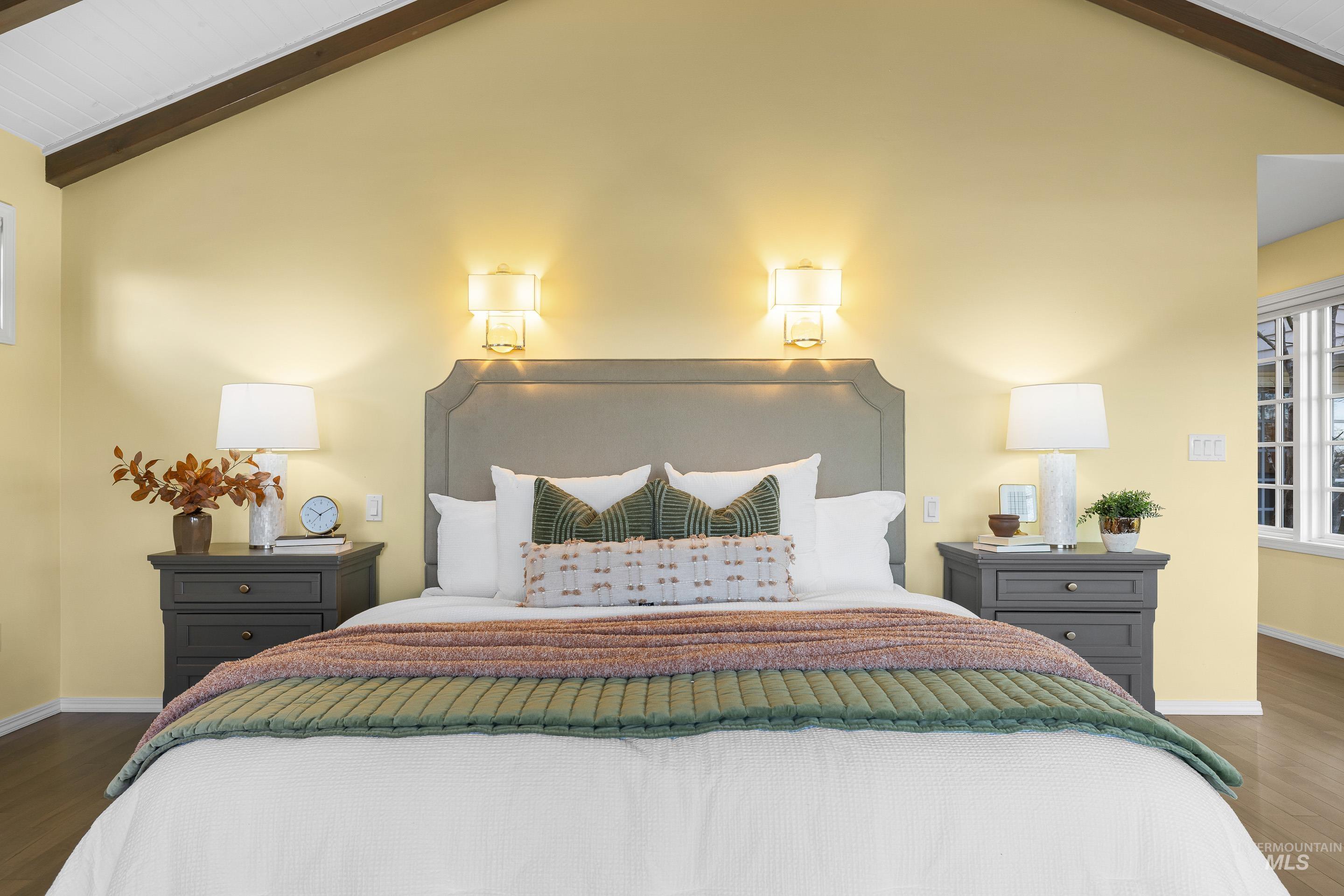 Bedroom with lofted ceiling with beams and wood finished floors
