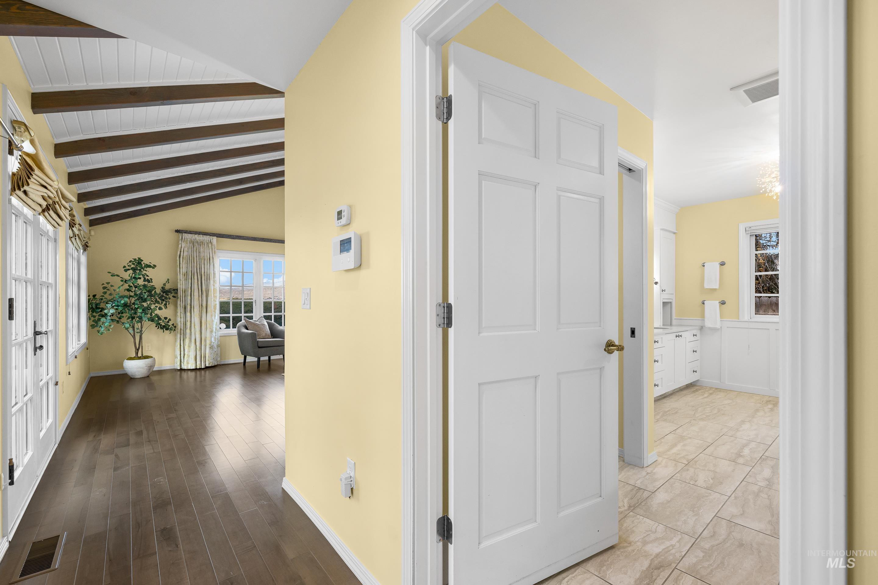 Hallway with vaulted ceiling with beams and baseboards