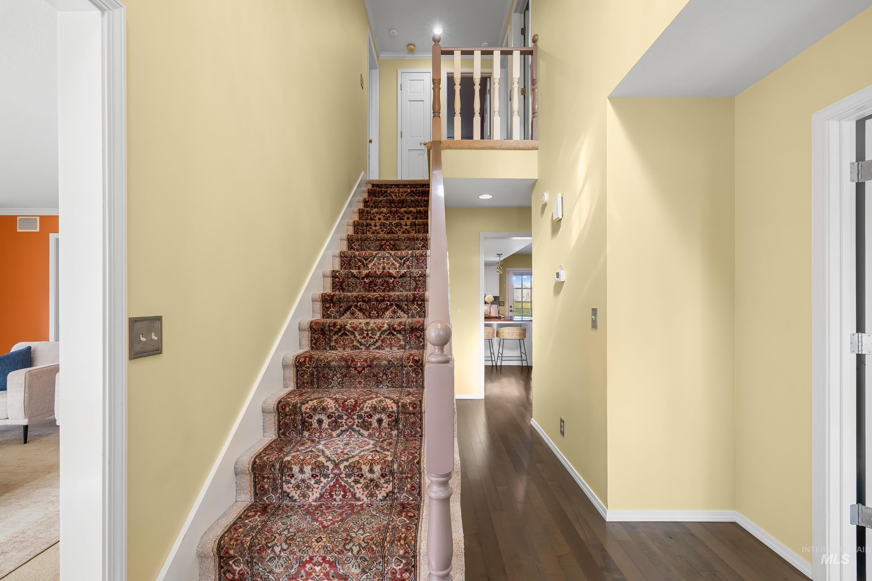 Stairs featuring recessed lighting, wood finished floors, a high ceiling, and ornamental molding