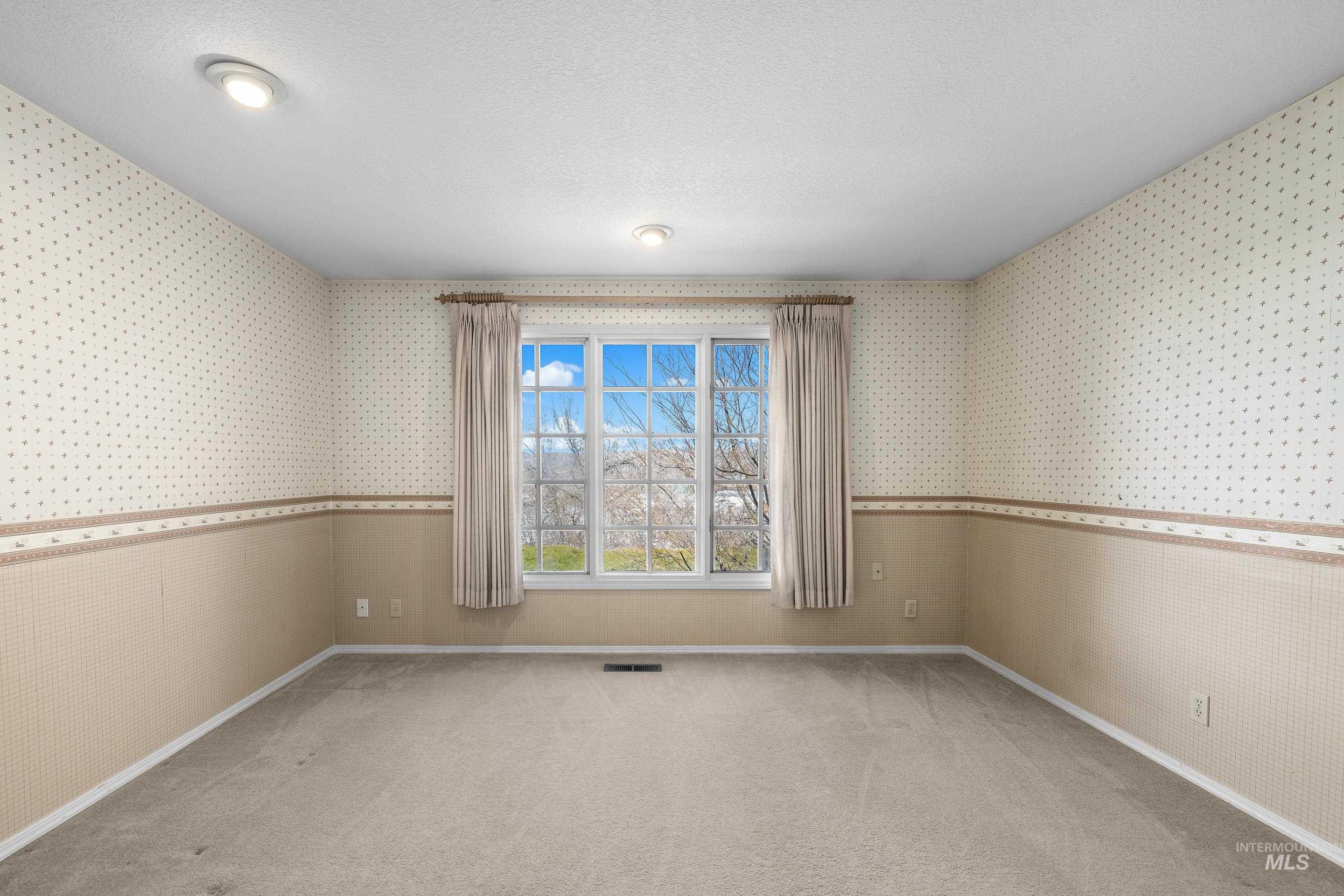 Spare room featuring wallpapered walls, light carpet, and a textured ceiling