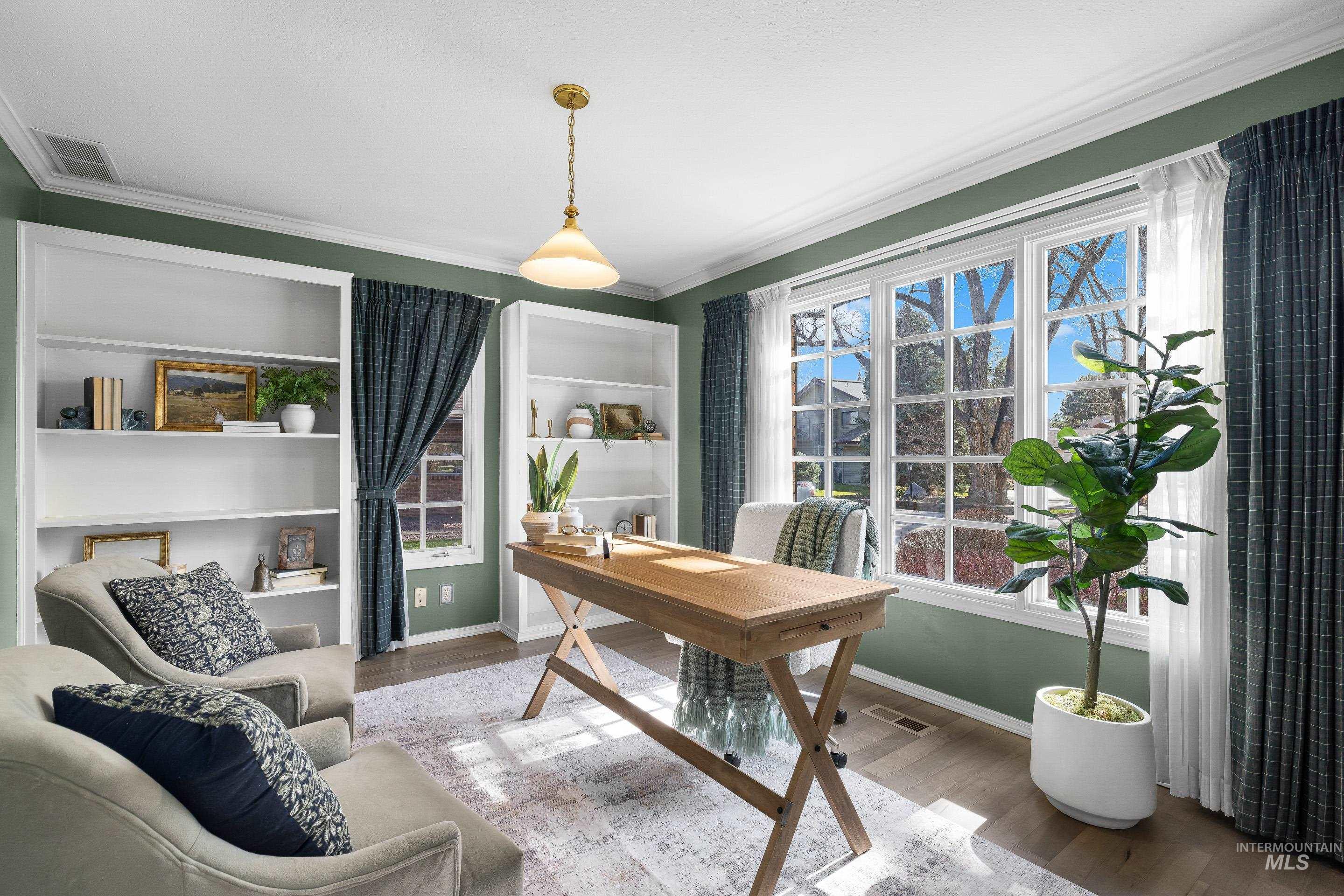 Office space featuring wood finished floors, built in shelves, ornamental molding, and healthy amount of natural light