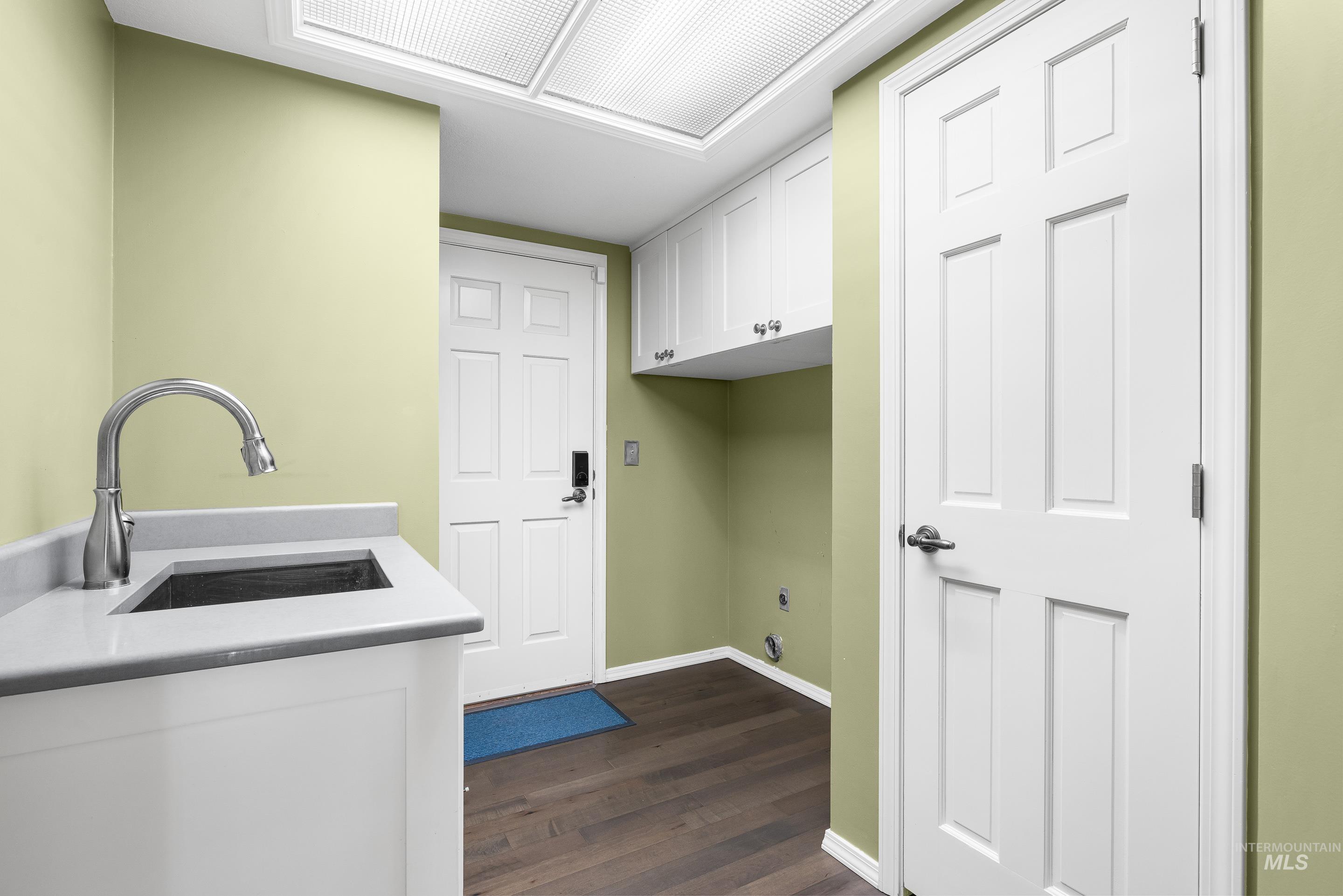 Laundry room featuring cabinet space and dark wood-style floors