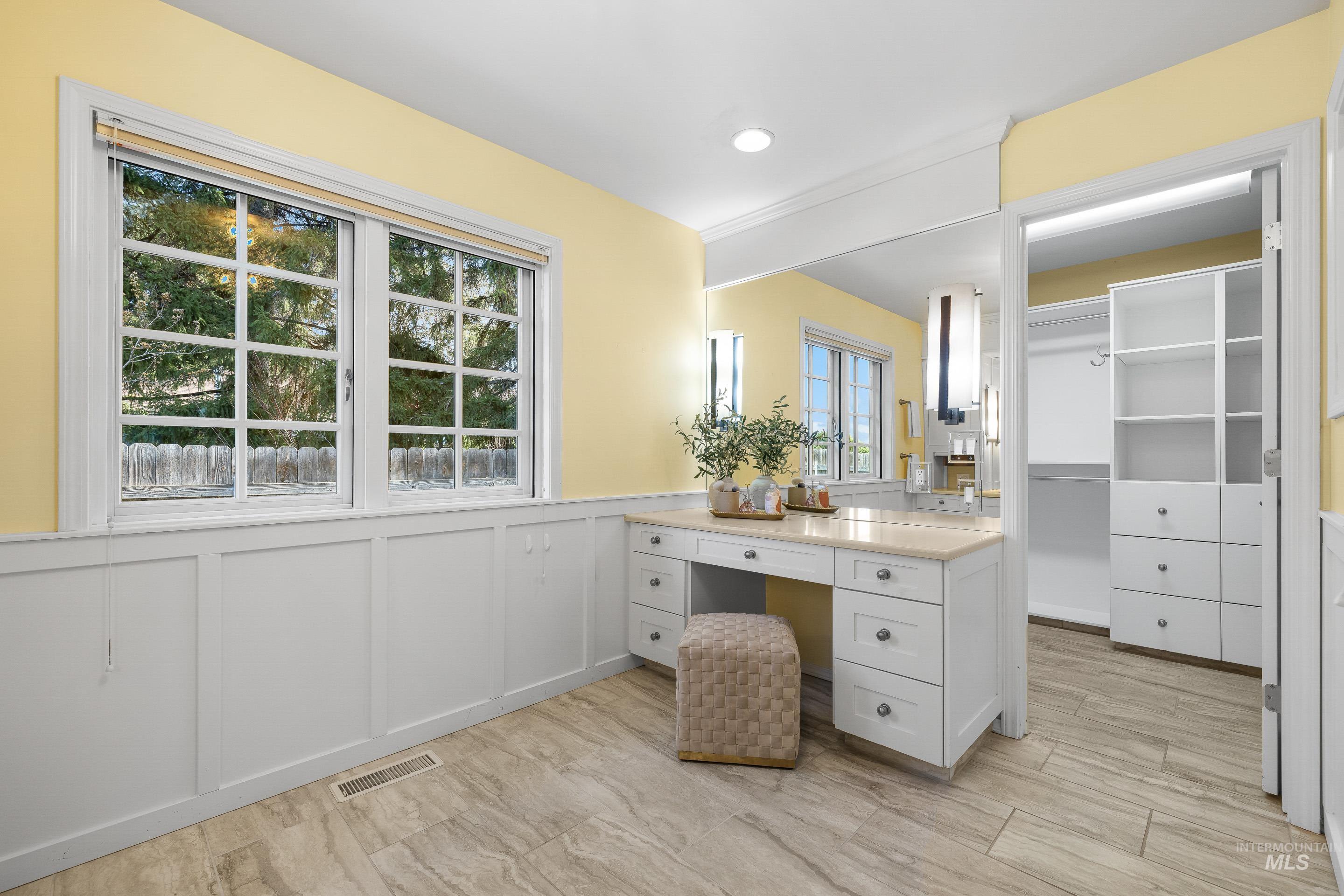 Full bath featuring a decorative wall, wainscoting, a walk in closet, and vanity