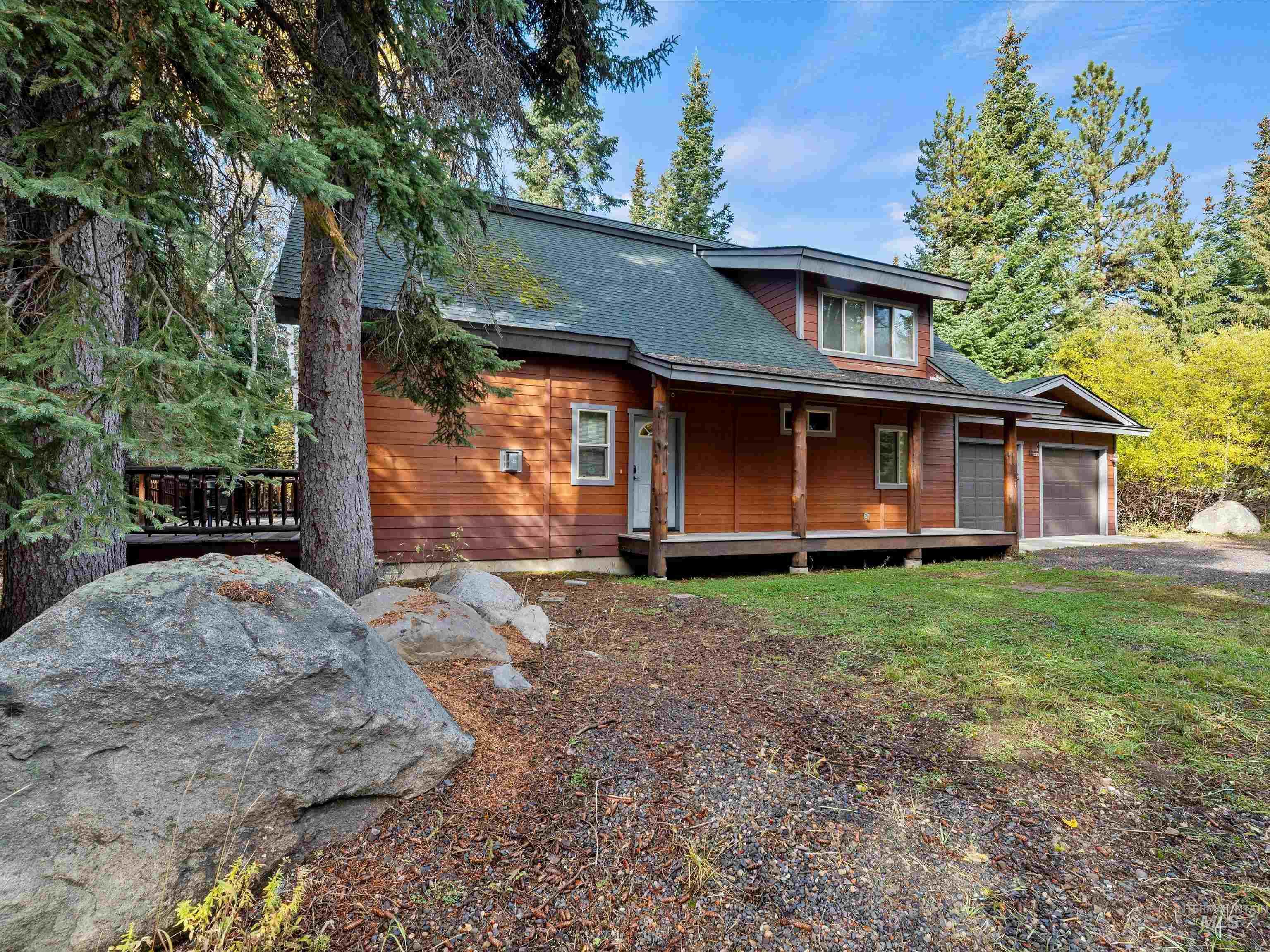 View of front of home featuring a deck, roof with shingles, and driveway