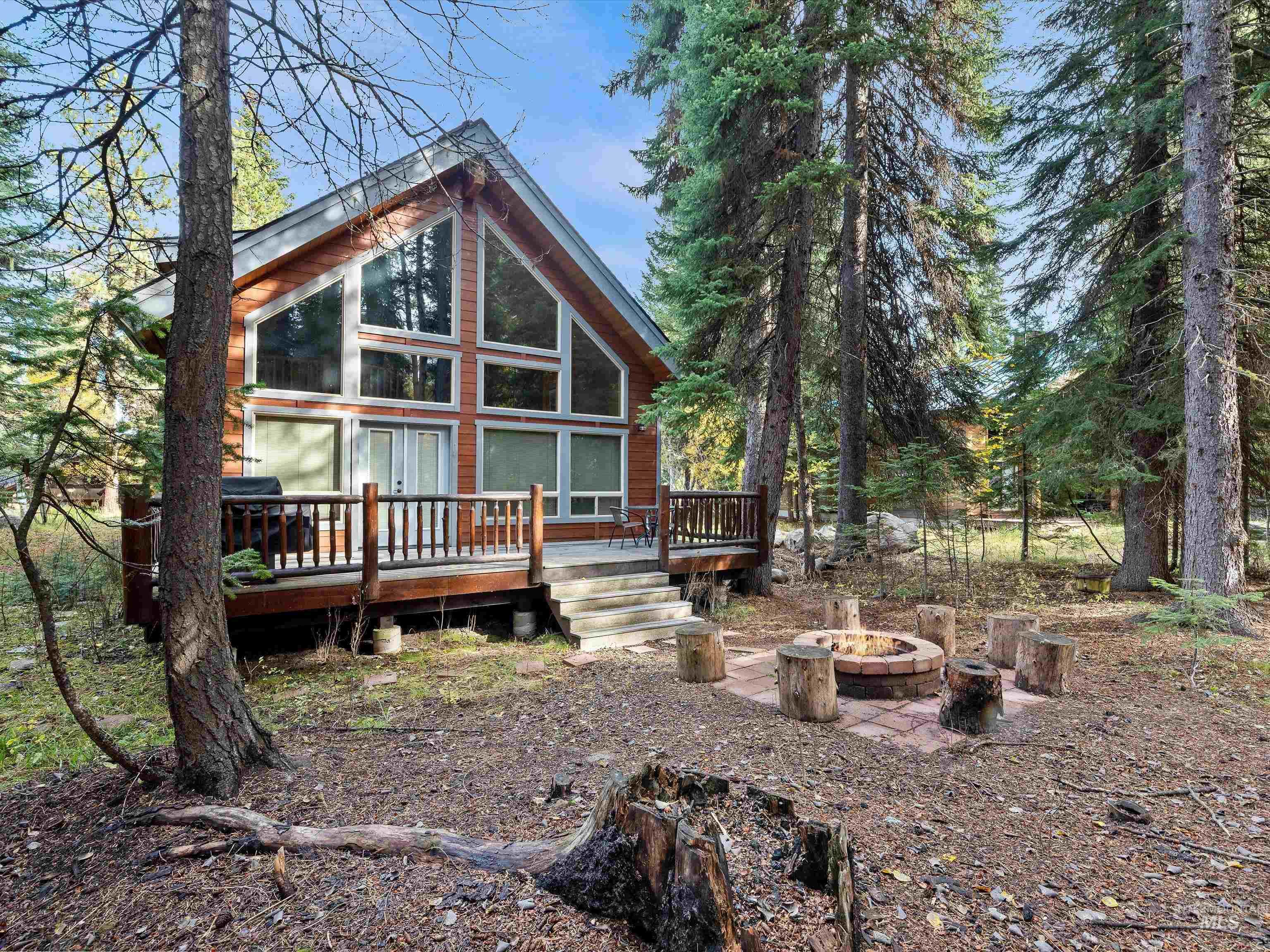 Rear view of property featuring a fire pit, a wooden deck, and a sunroom