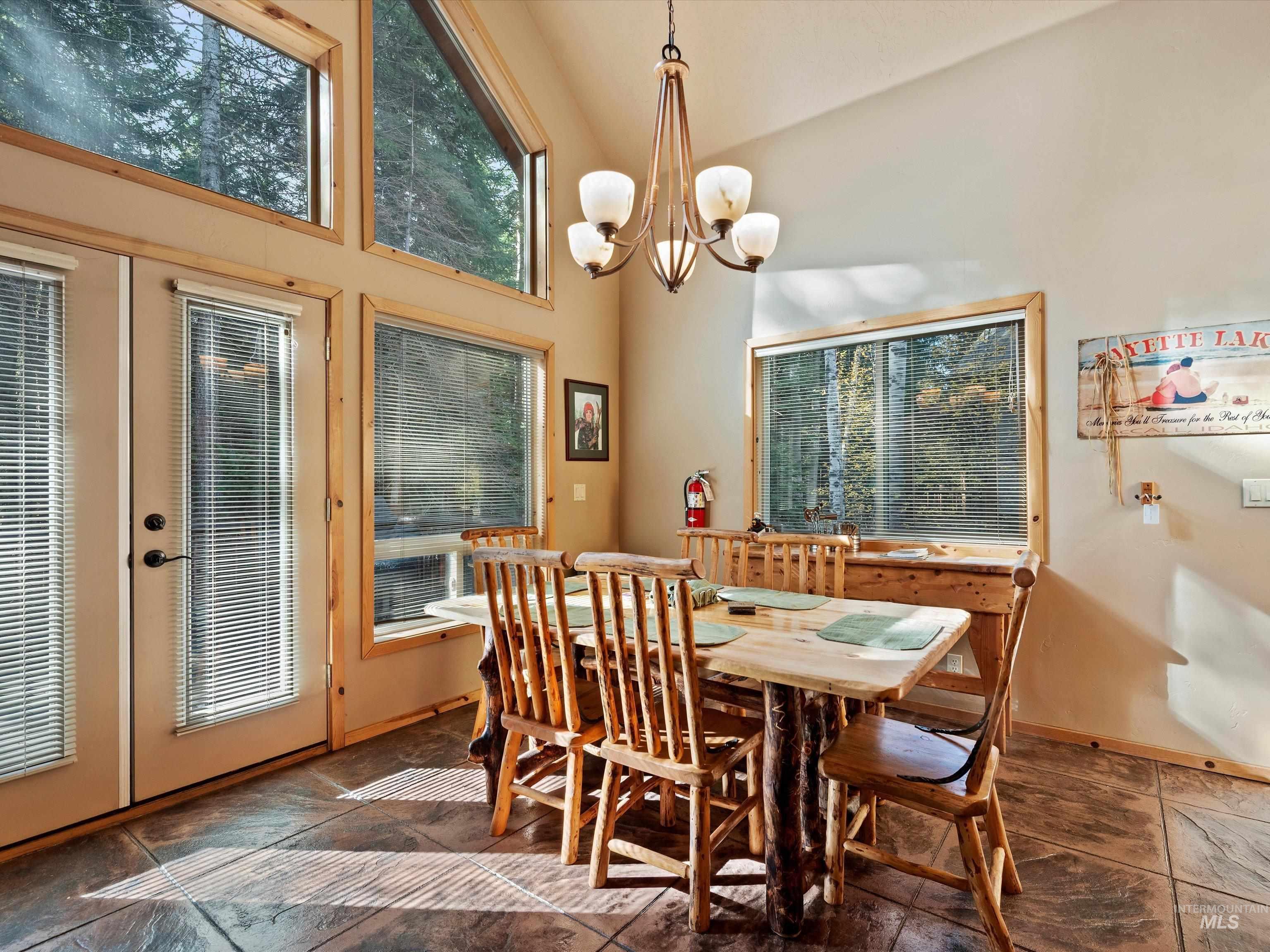 Dining room featuring high vaulted ceiling, french doors, and a chandelier
