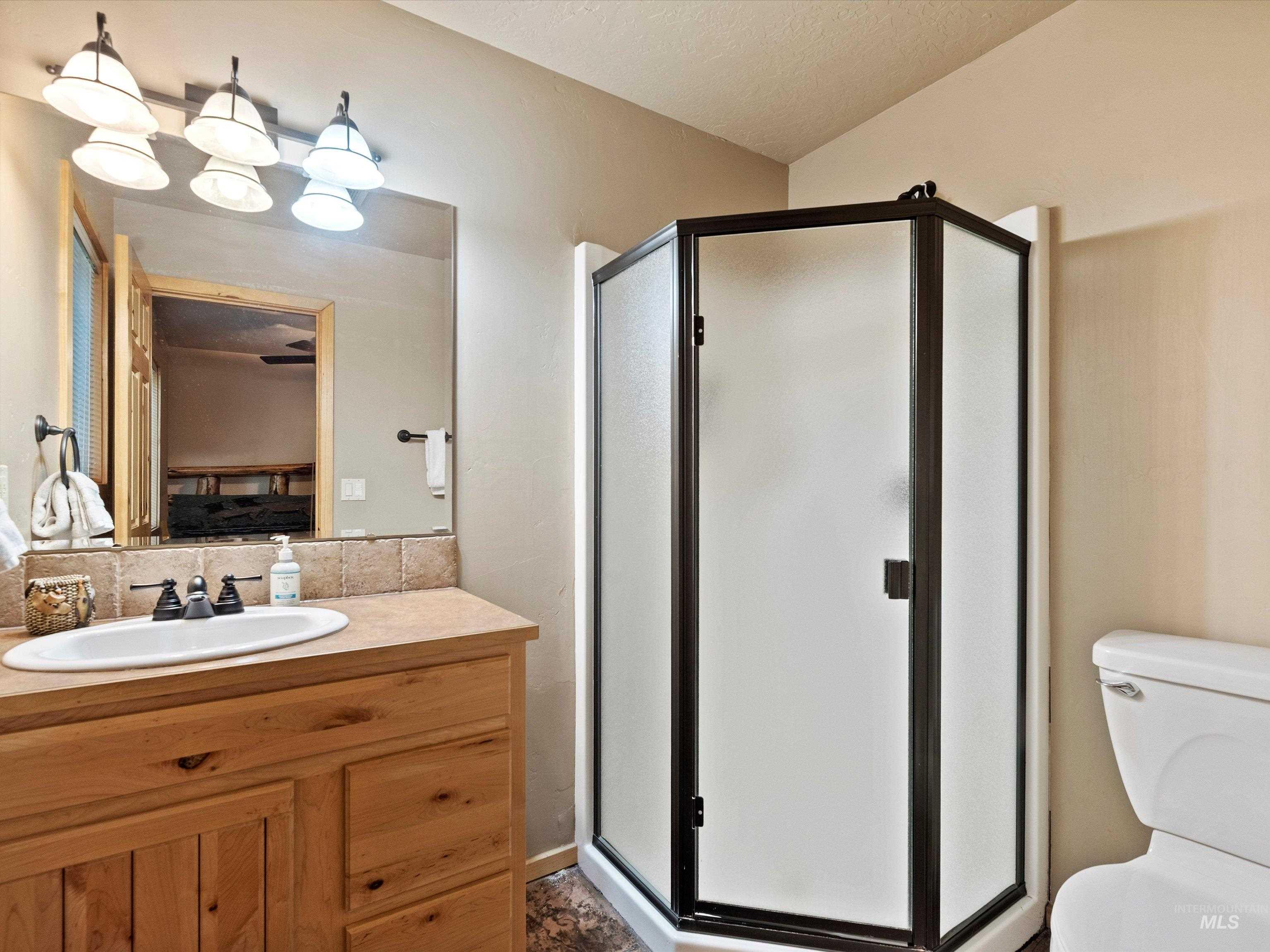 Ensuite bathroom with a stall shower, vanity, and a textured ceiling