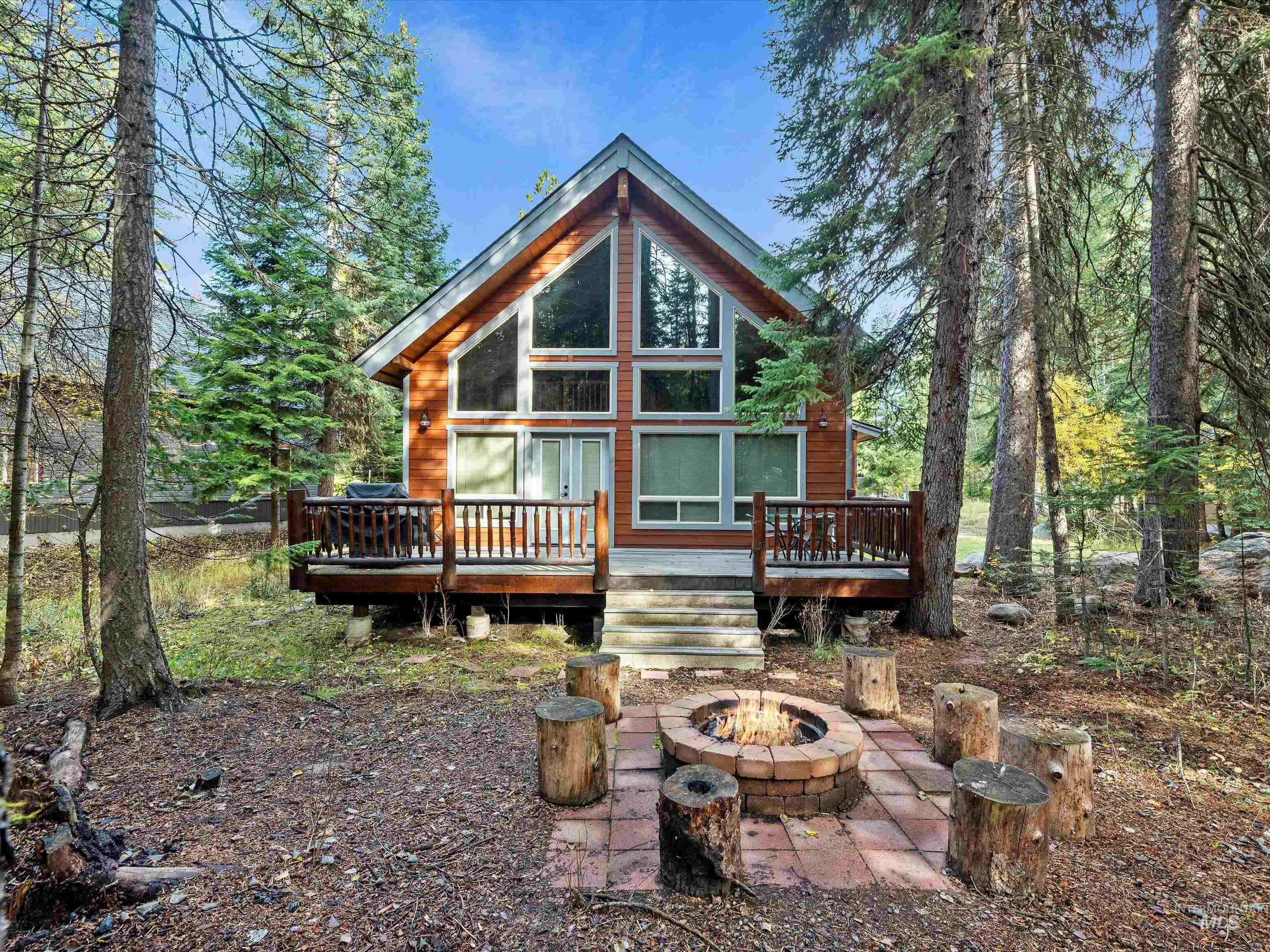 Back of property with a wooden deck and a fire pit