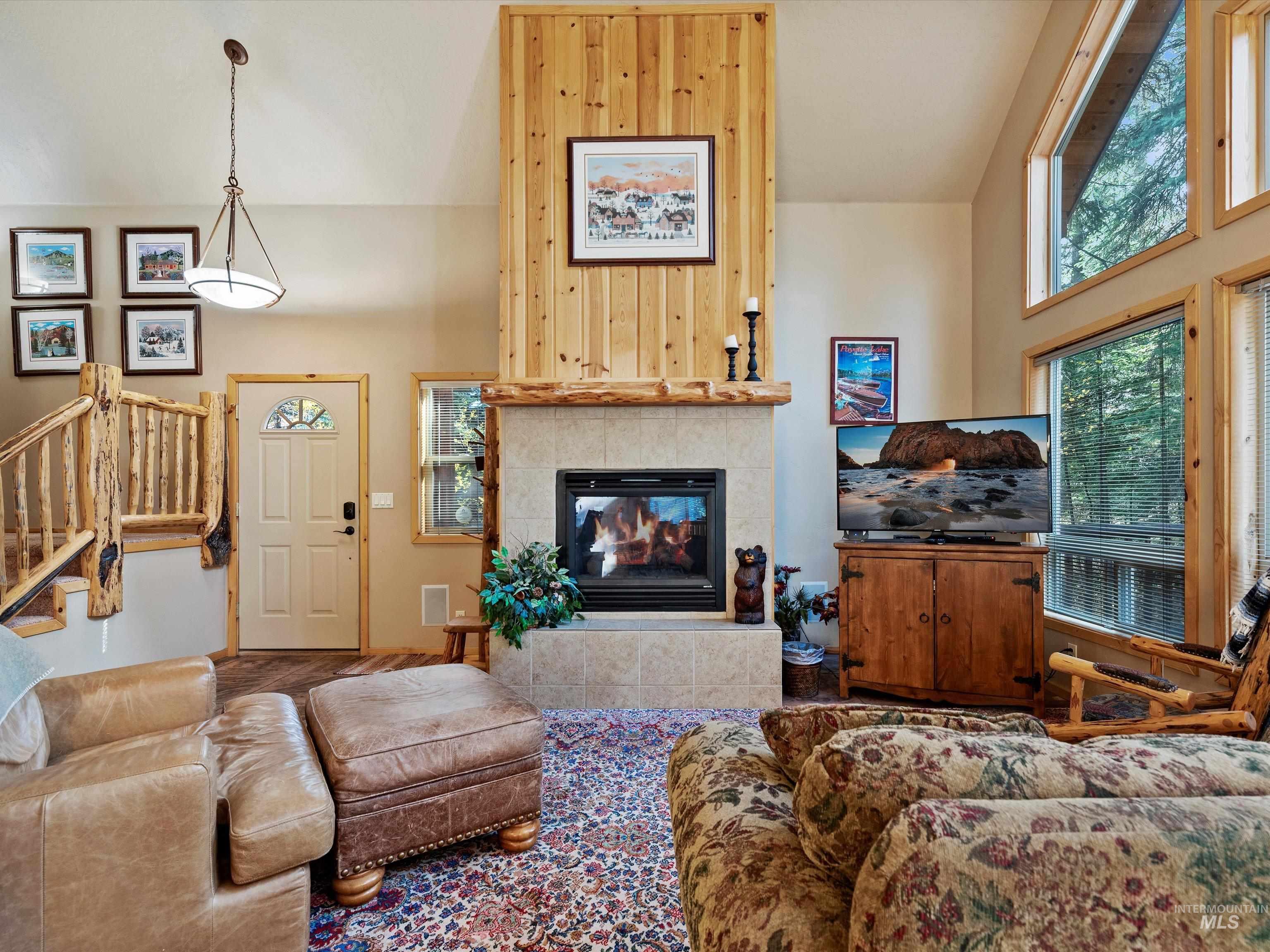 Living room with high vaulted ceiling, a fireplace, and stairs