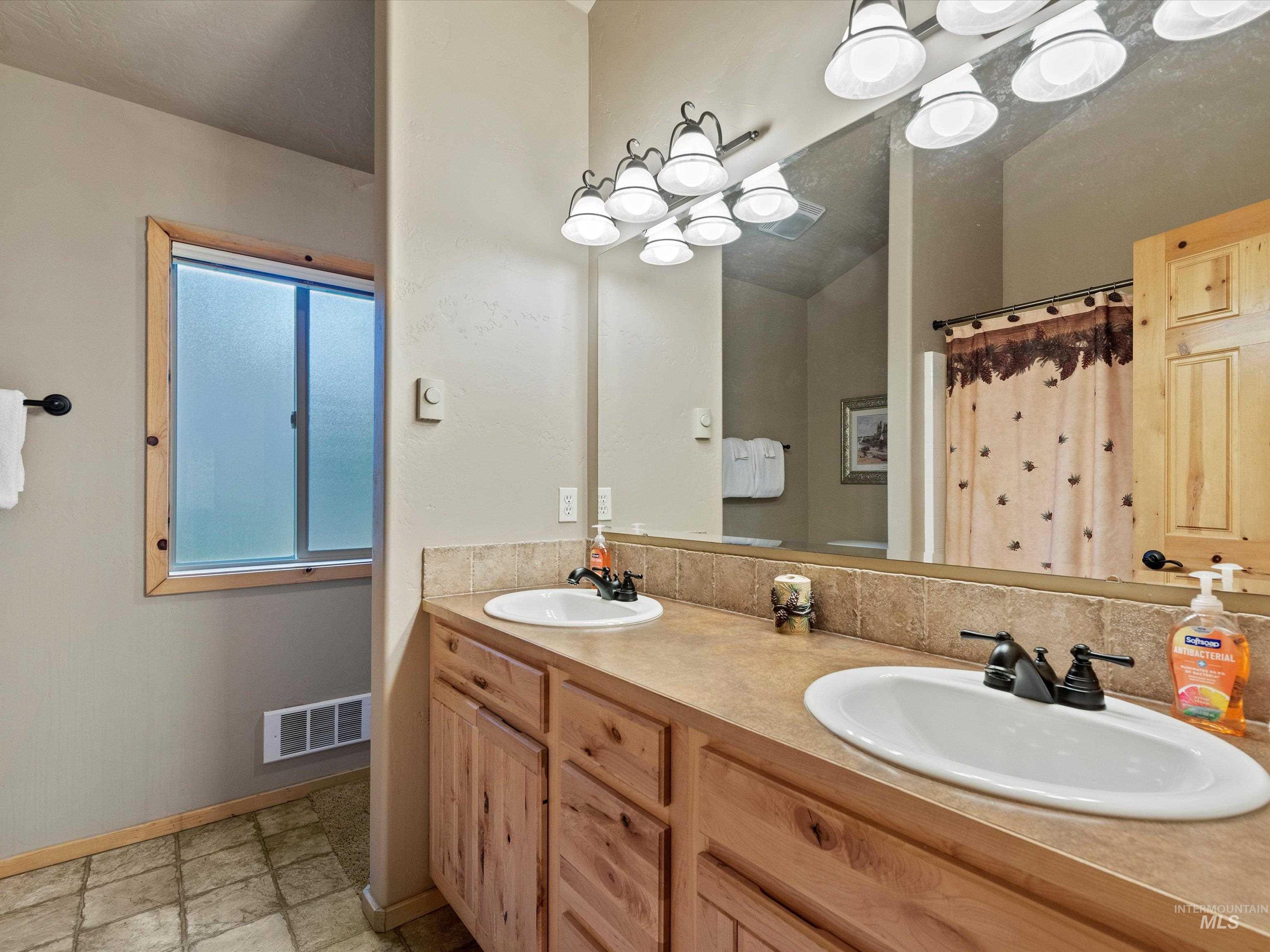 Bathroom featuring double vanity, a shower with shower curtain, and tasteful backsplash