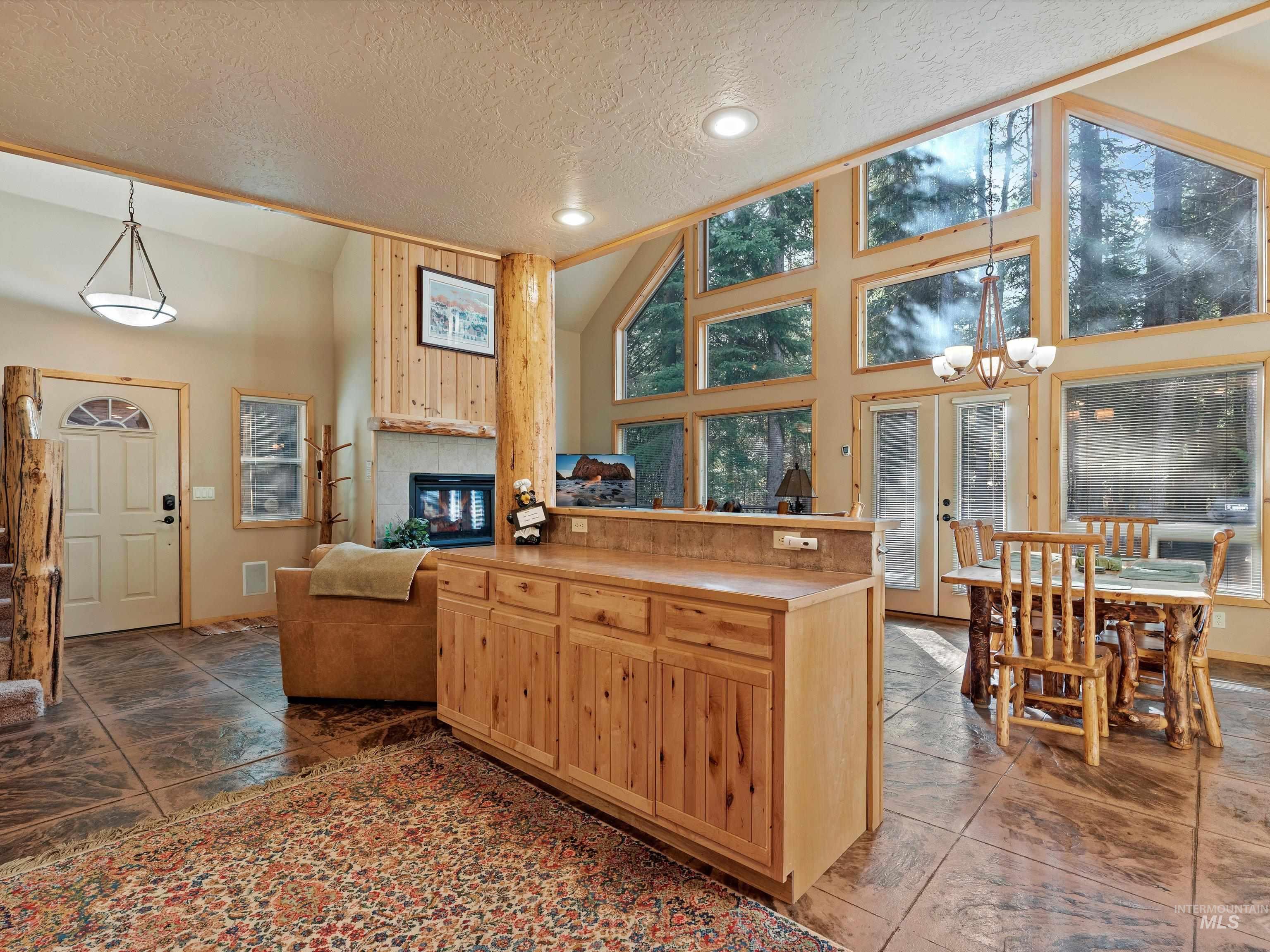 Kitchen featuring pendant lighting, a textured ceiling, high vaulted ceiling, light countertops, and light brown cabinets