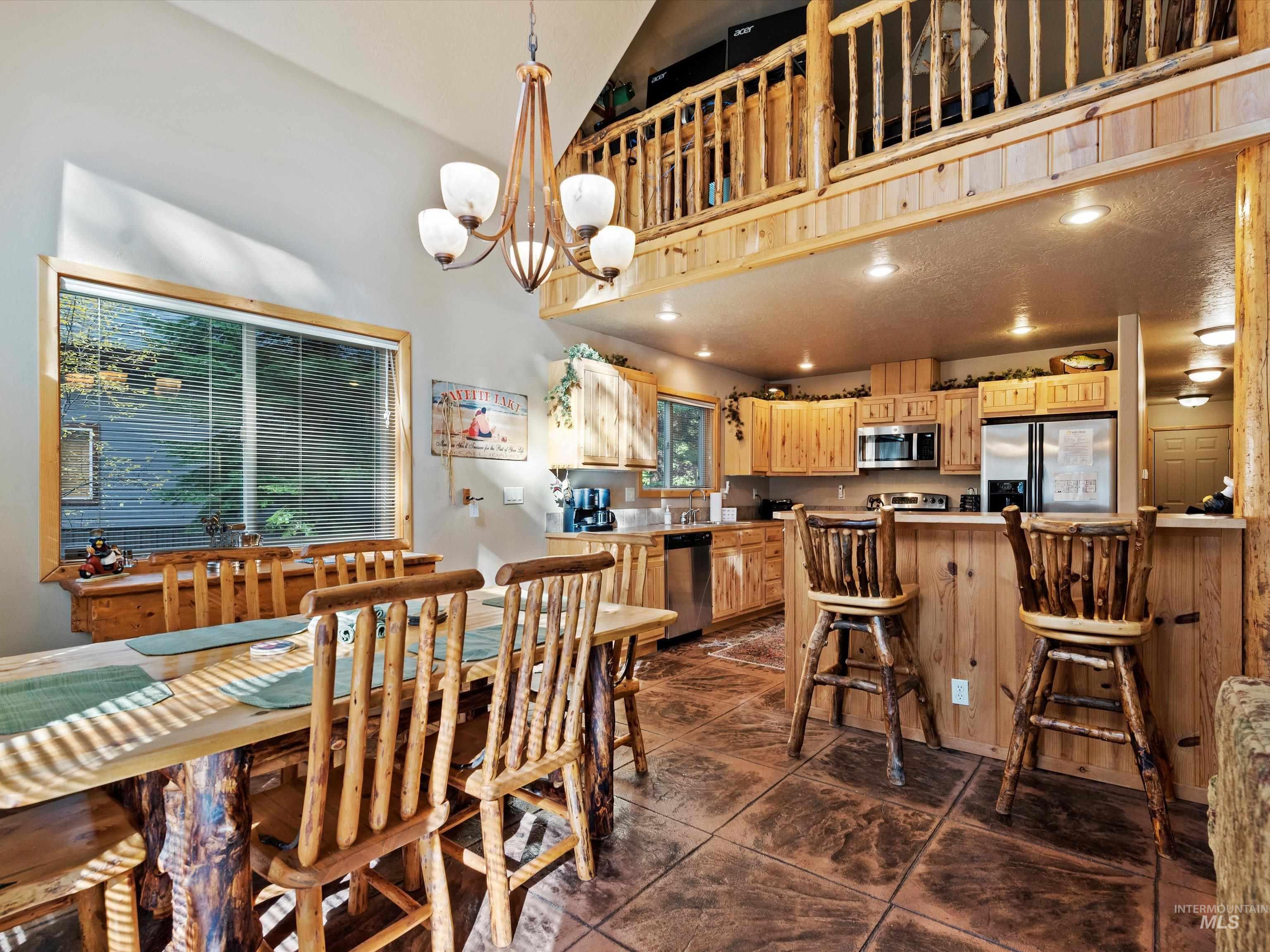 Dining area featuring a chandelier, recessed lighting, dark tile patterned floors, and high vaulted ceiling