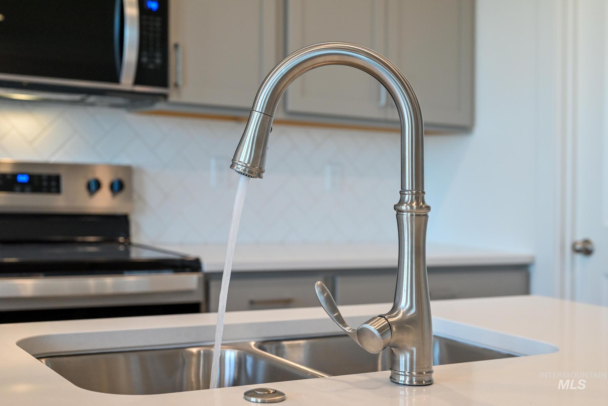 Kitchen view of stainless steel appliances, gray cabinetry, and light stone countertops