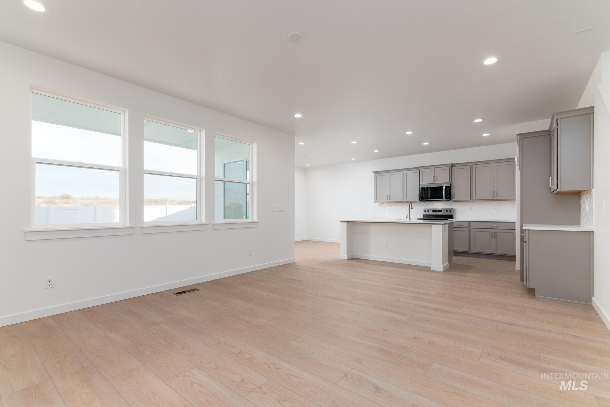 Kitchen featuring a kitchen island with sink, recessed lighting, open floor plan, light countertops, and tasteful backsplash