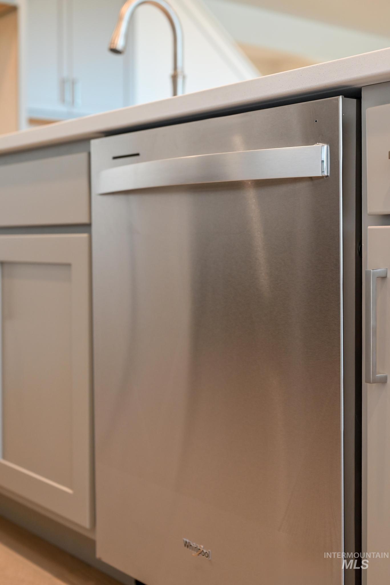 Kitchen view of stainless steel dishwasher and gray cabinetry