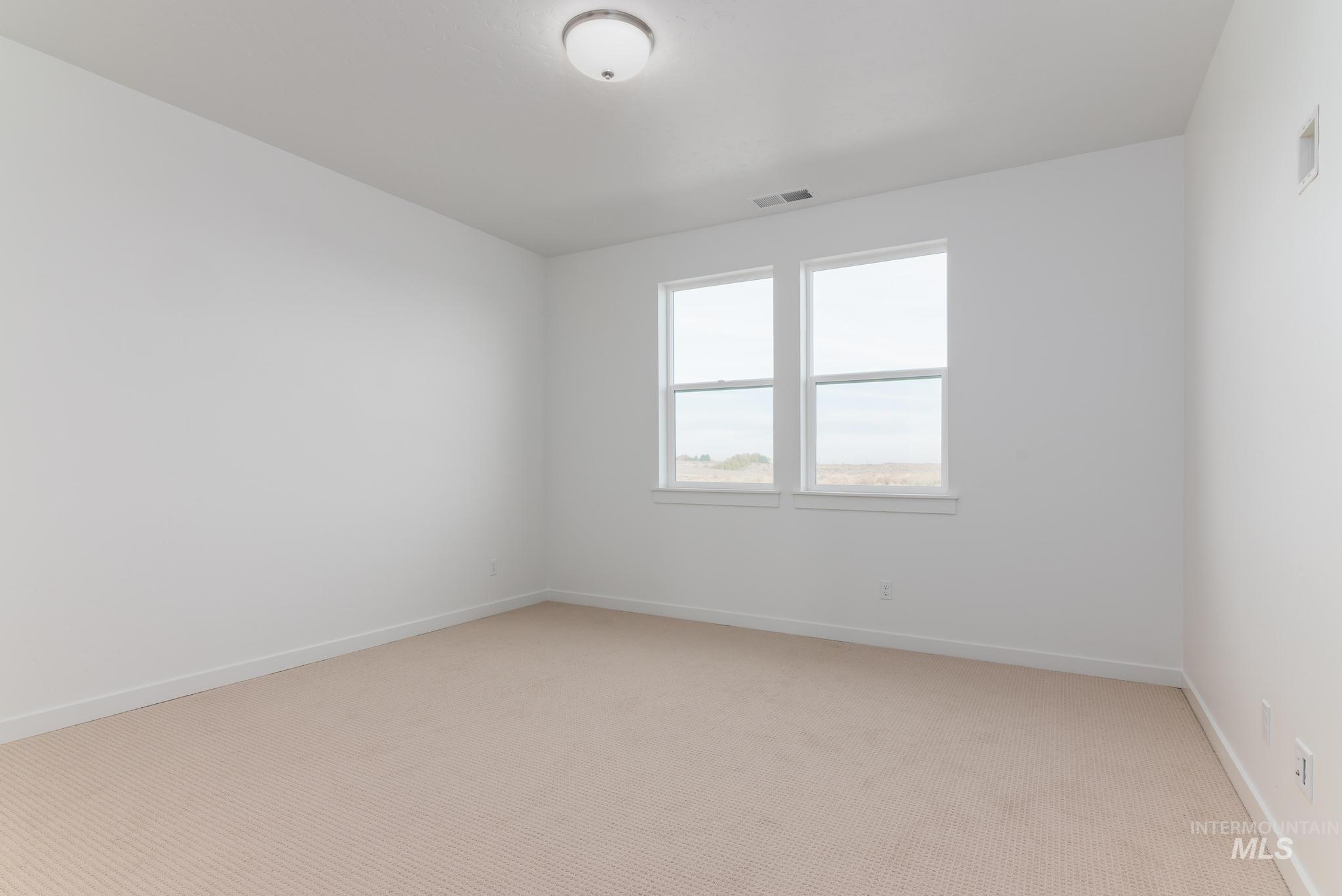 Unfurnished room featuring light carpet and baseboards