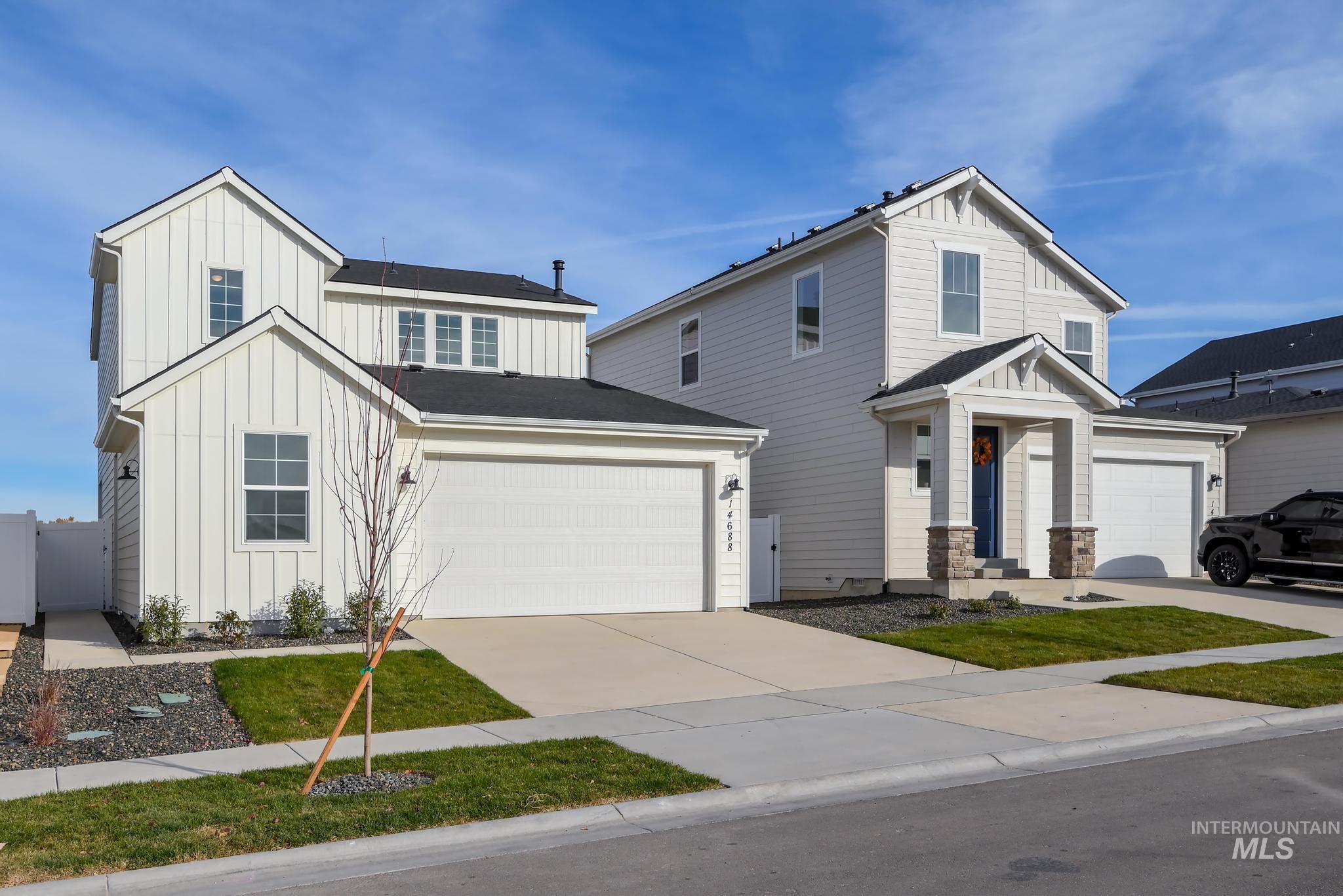 View of front facade with board and batten siding, driveway, and roof with shingles