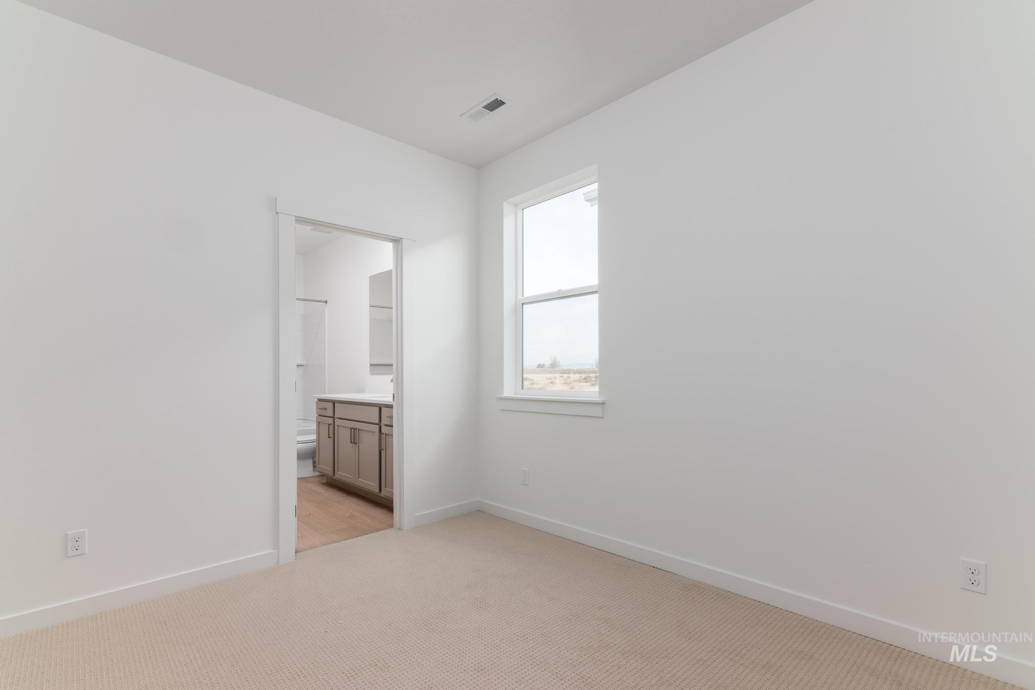 Unfurnished bedroom featuring light carpet and ensuite bathroom