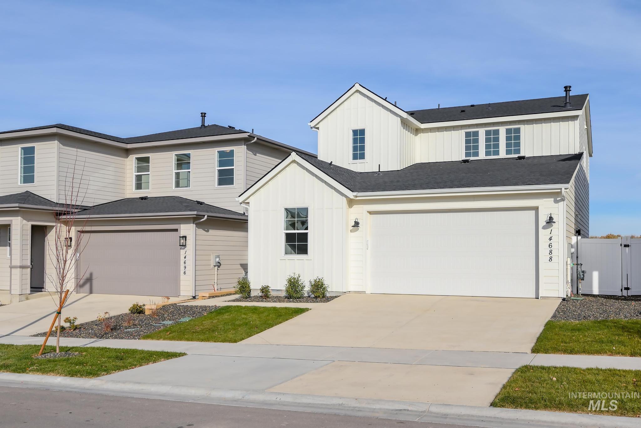 View of front of home with board and batten siding, concrete driveway, an attached garage, a gate, and a shingled roof