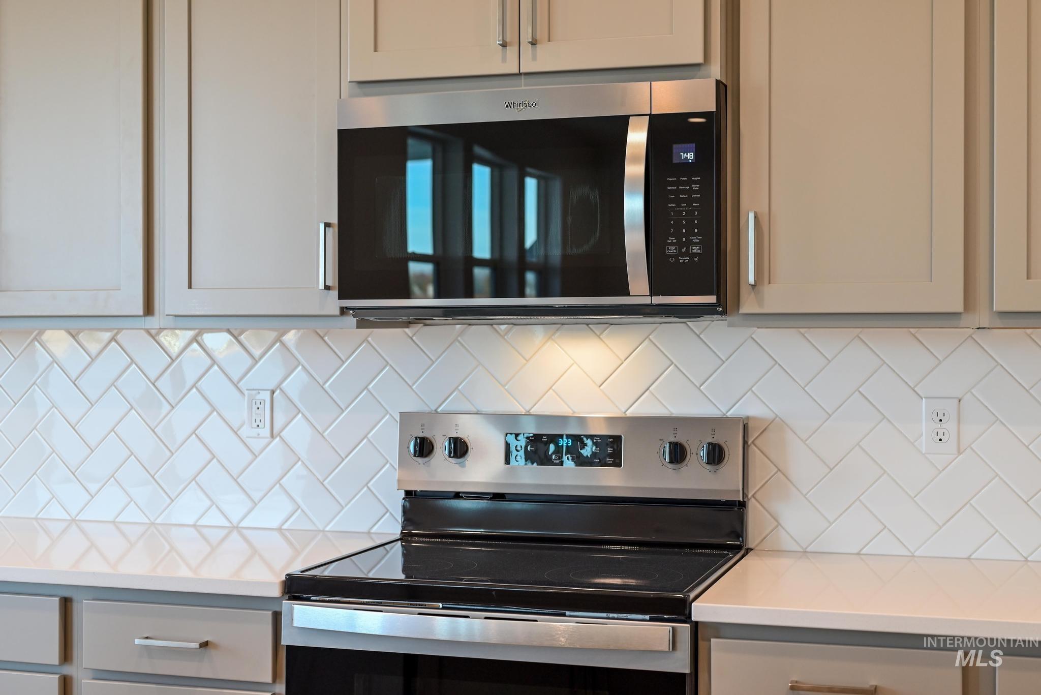 Kitchen with stainless steel appliances, light stone countertops, and tasteful backsplash