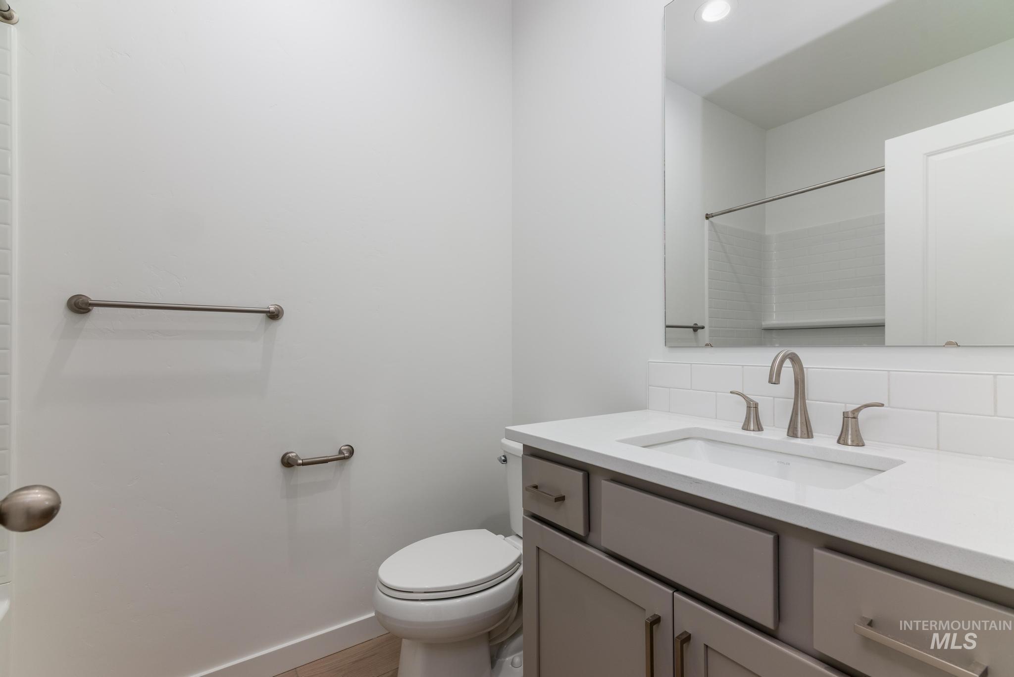 Bathroom with vanity, decorative backsplash, a shower, and light wood-type flooring