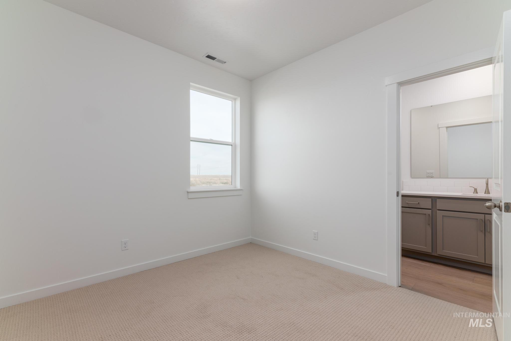 Unfurnished bedroom featuring light colored carpet and connected bathroom