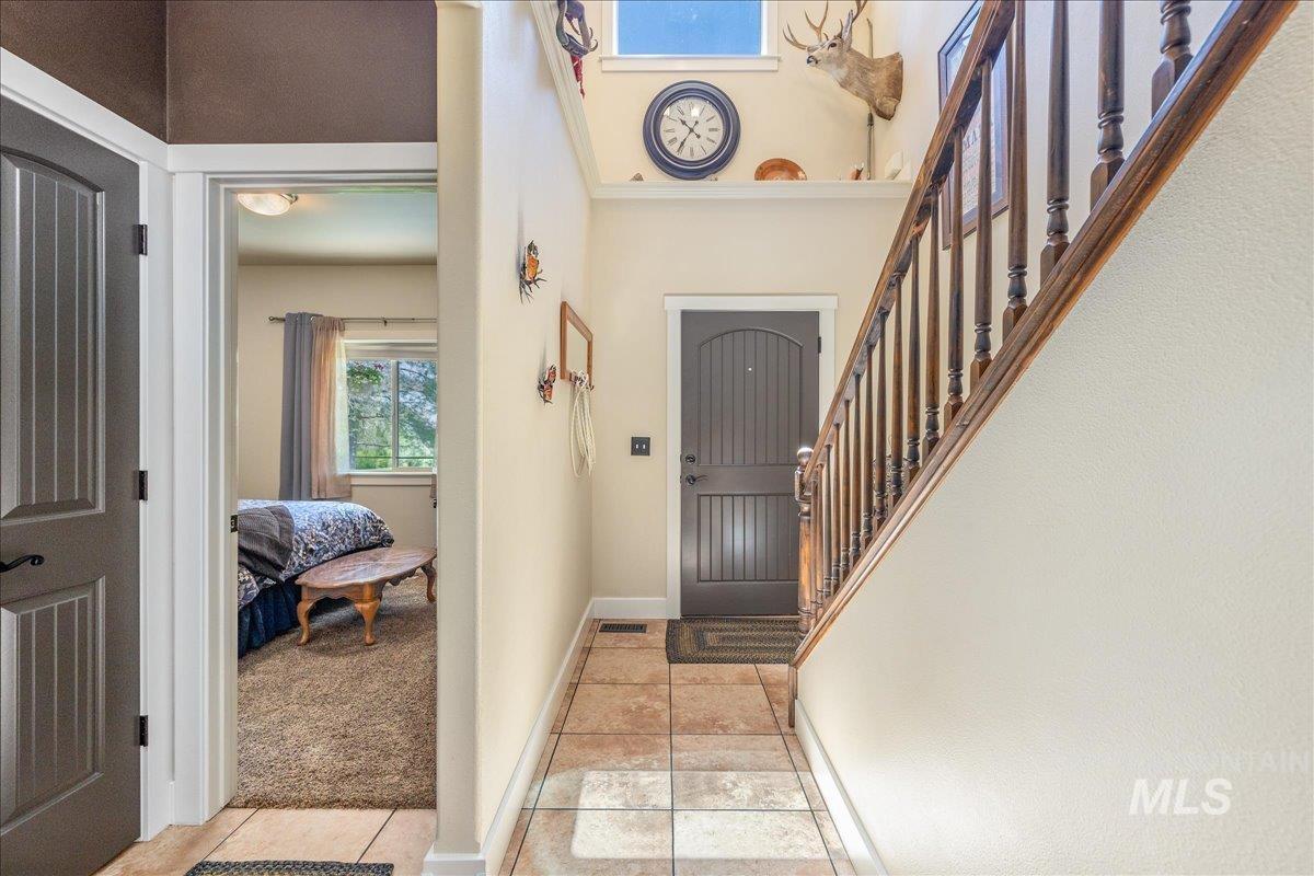 Entryway featuring tile flooring, a dark paneled door, and a wood staircase with balusters