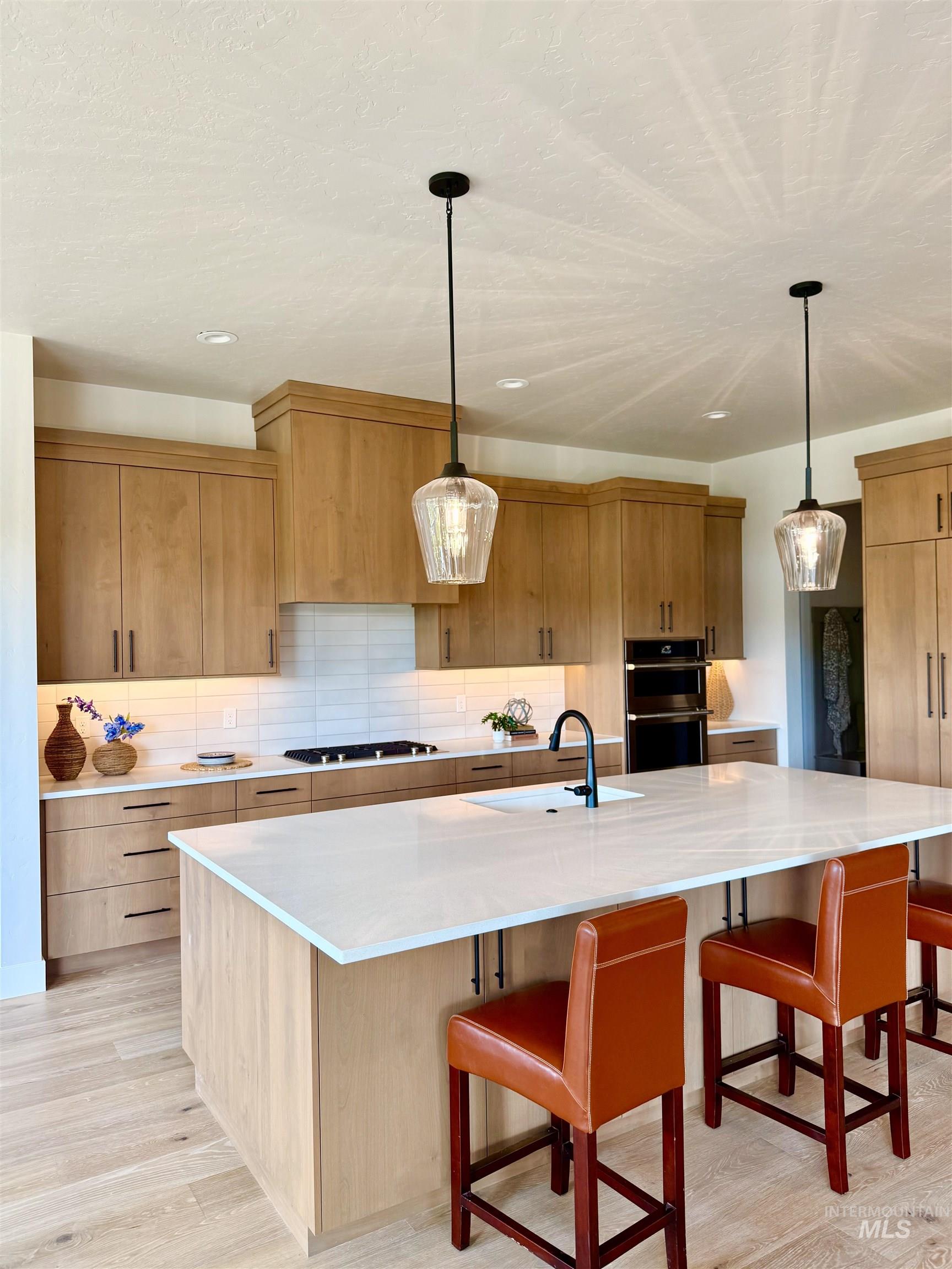 Kitchen with a large island, backsplash, a breakfast bar area, and light wood finished floors