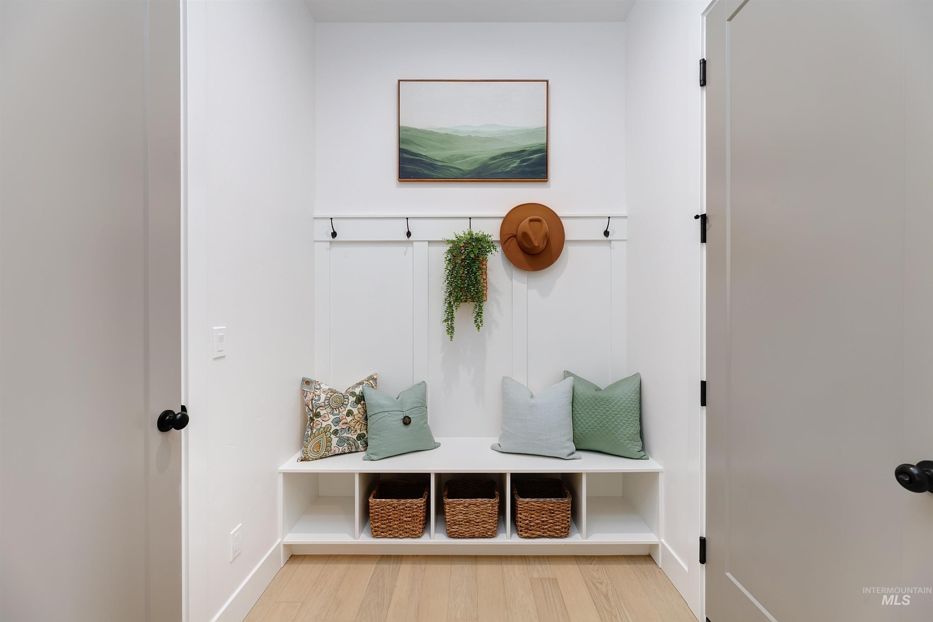 Entryway featuring a built-in bench with integrated cubby storage, wainscoting paneling, and black coat hooks