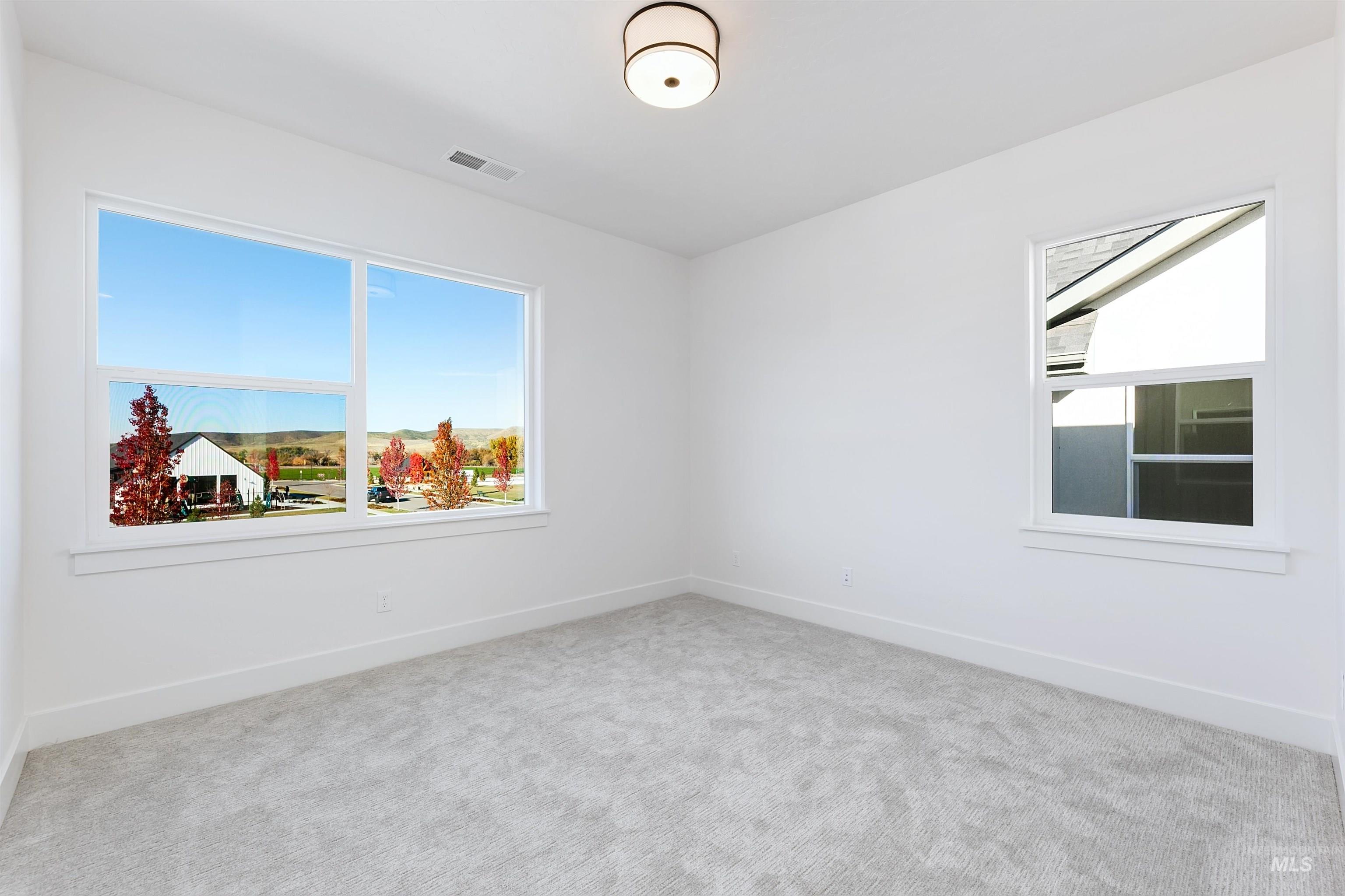 Bright room with white walls, light gray carpeting, and multiple windows