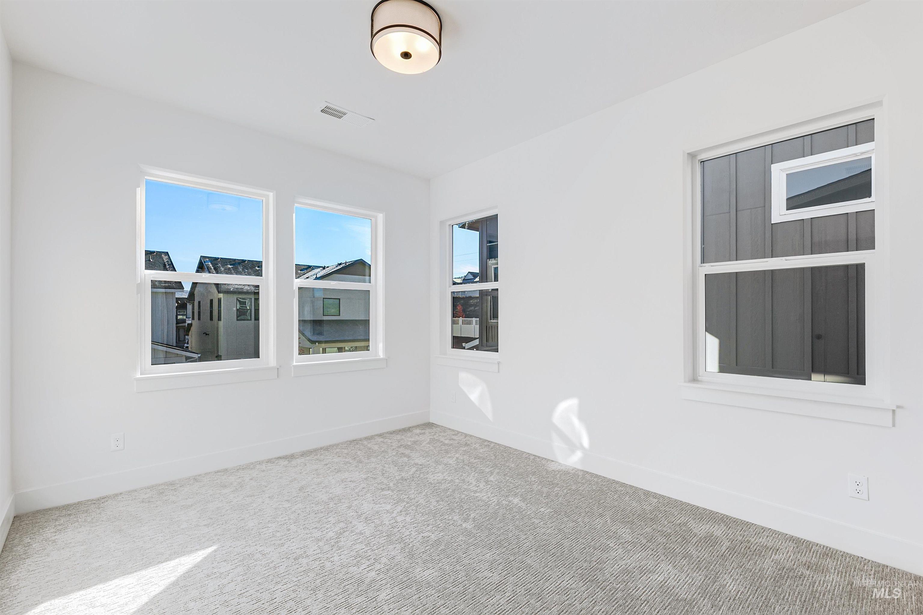 Bright room with white painted walls, crisp white trim, and light gray patterned carpeting