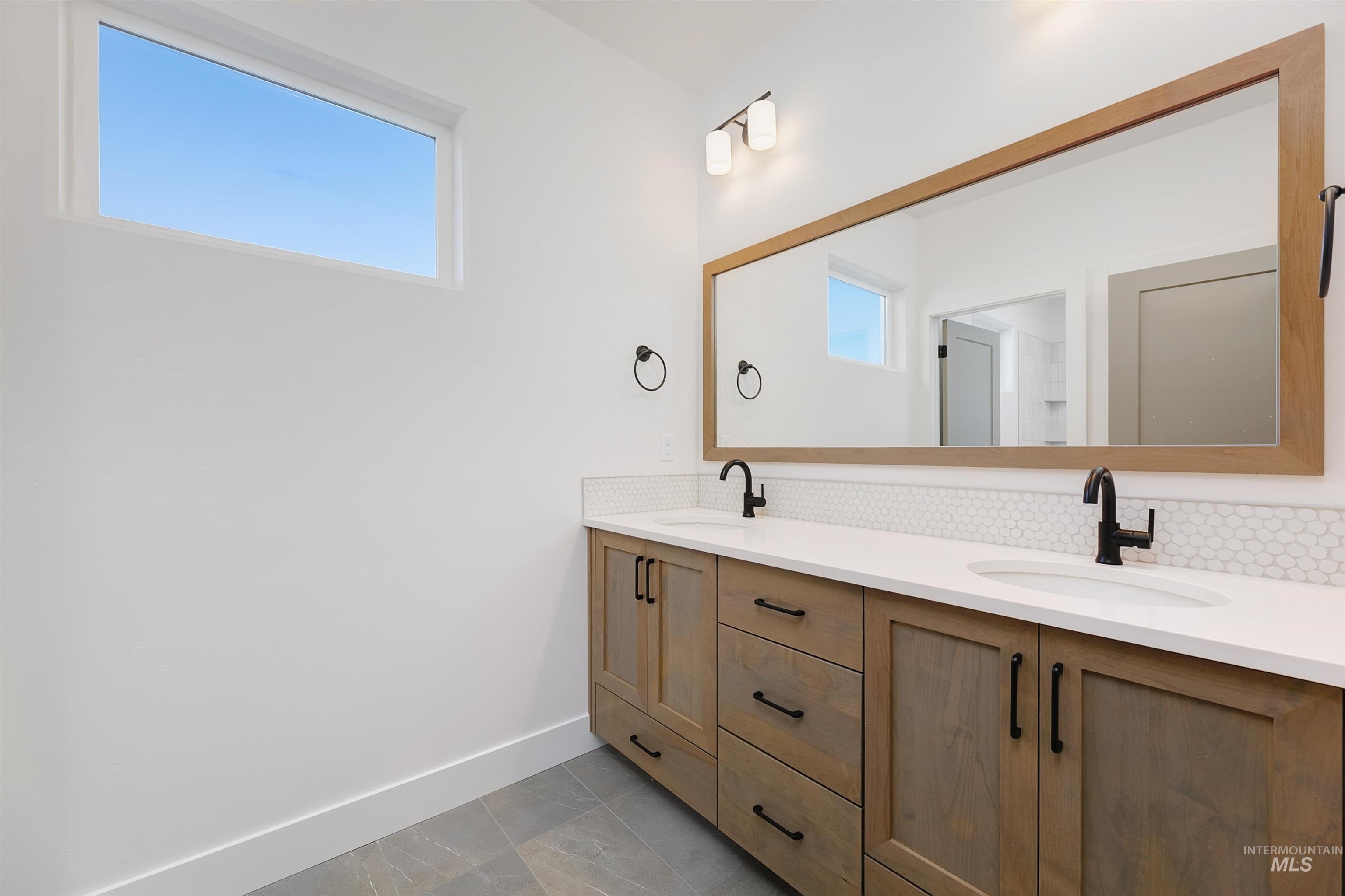 Double vanity featuring wood-finish cabinetry, white countertops, and matte black hardware