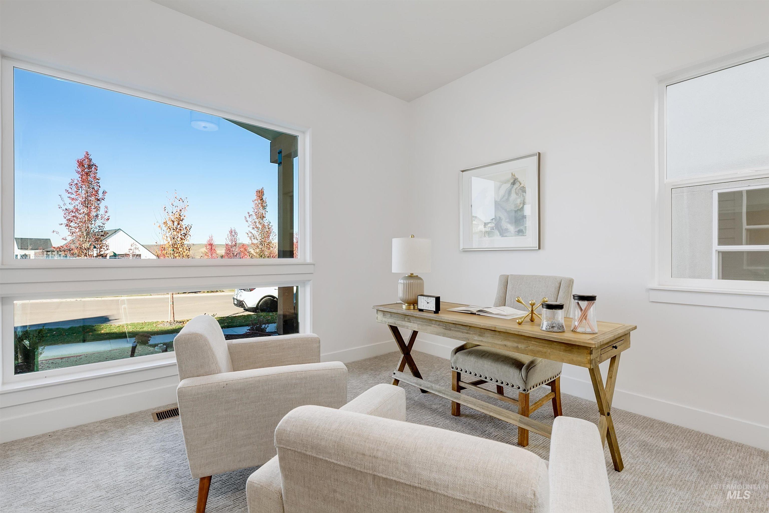 Bright room with white painted walls, light gray carpeting, and extensive natural light from a large horizontal picture window and an additional window