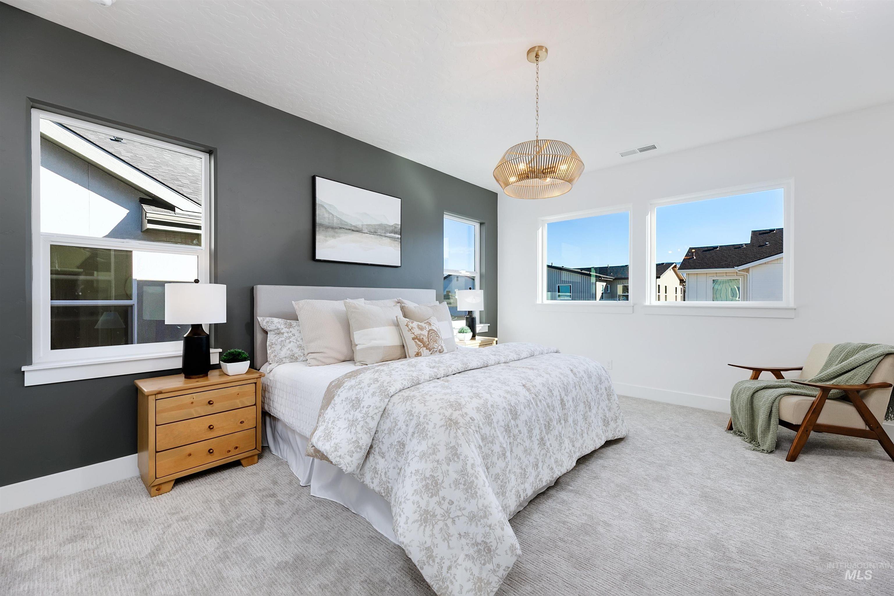 Spacious bedroom featuring light gray carpeting, a dark accent wall, and three large windows